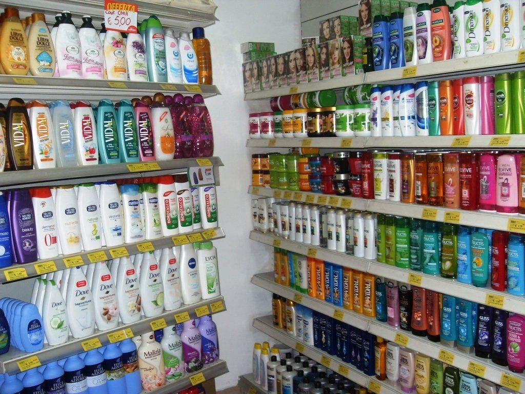 Un corridoio di un negozio pieno di file di coloratissime bottiglie di shampoo e prodotti per la cura dei capelli sugli scaffali.