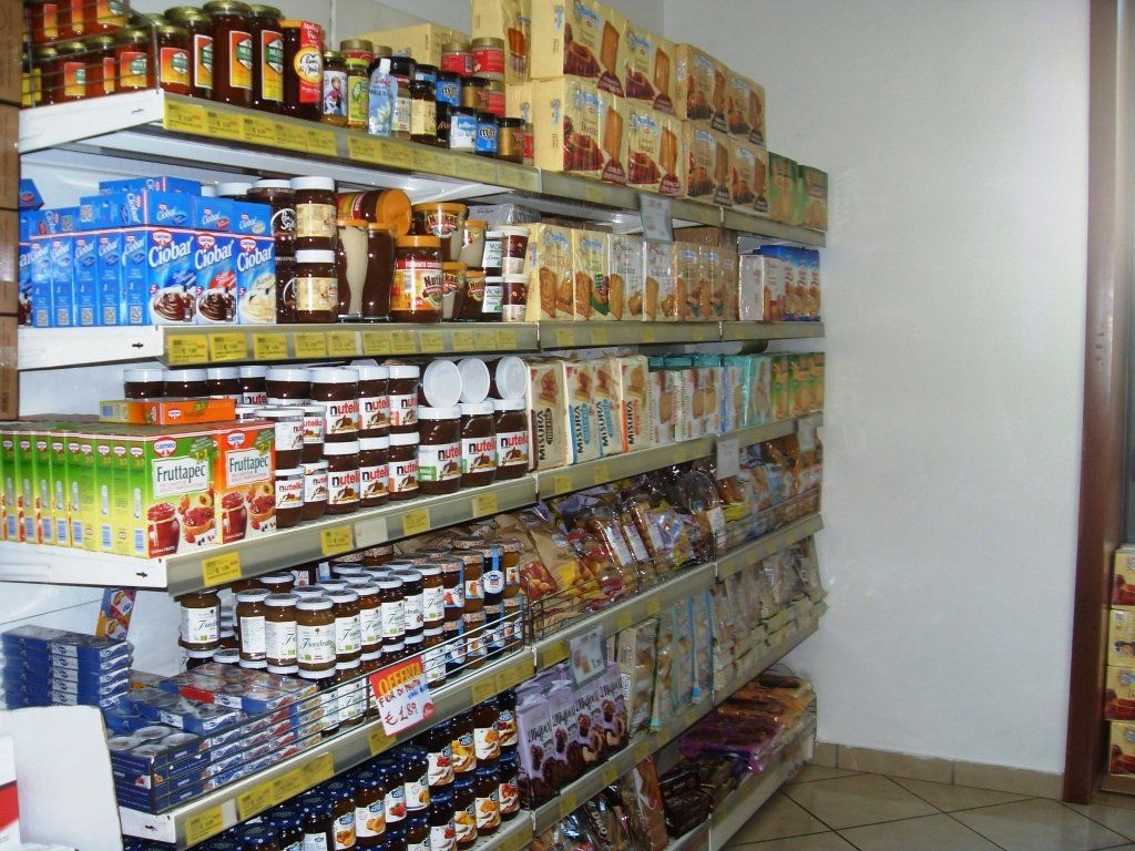 Scaffali pieni di generi alimentari confezionati in una piccola corsia di un minimarket.
