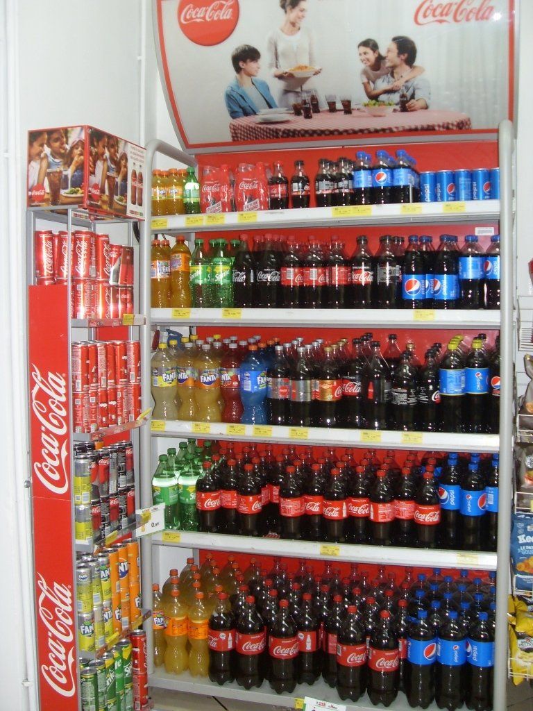 Frigorifero espositore Coca-Cola con bottiglie e lattine contrassegnate da etichette rosse in un negozio
