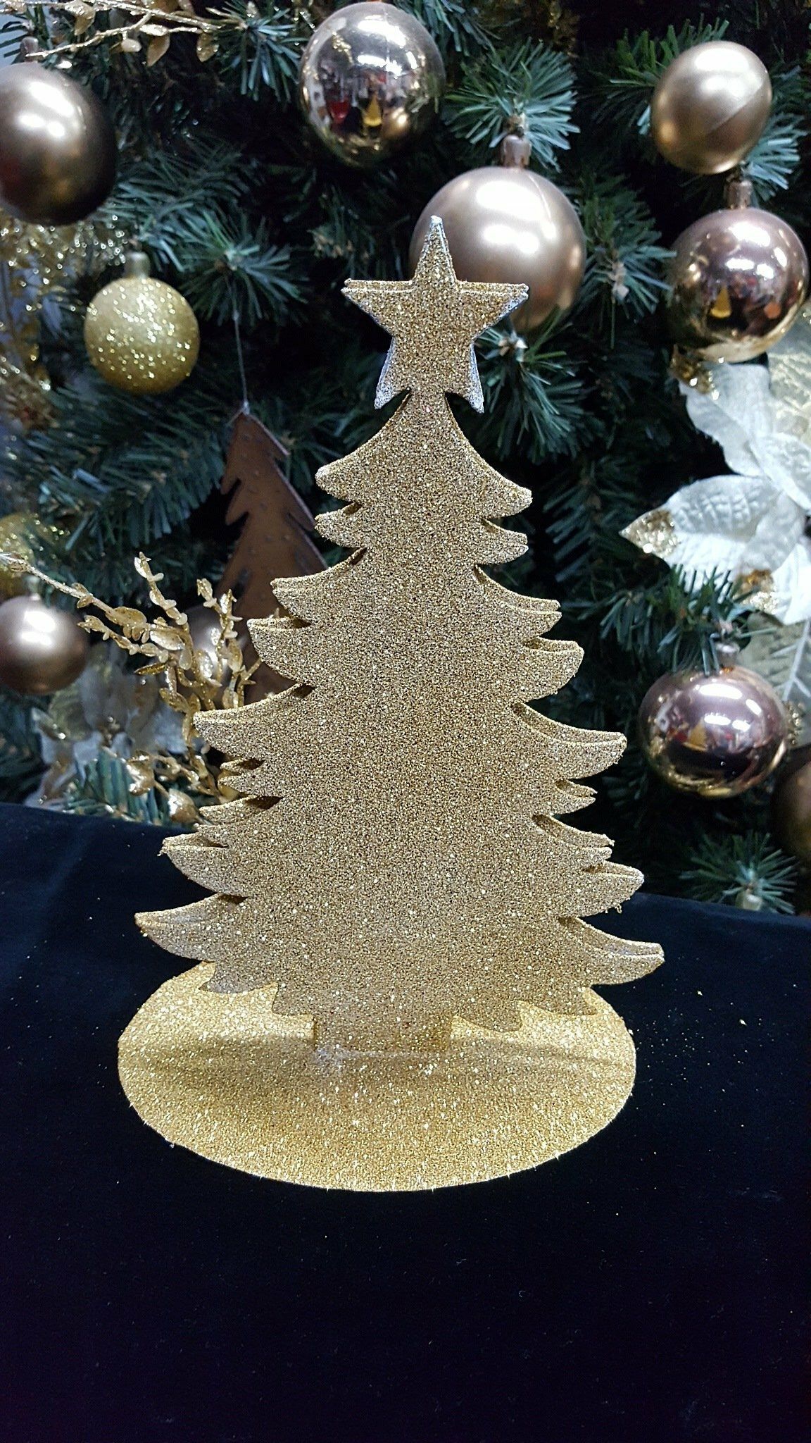Adorno navideño dorado brillante con estrella en la punta, frente a las decoraciones navideñas.