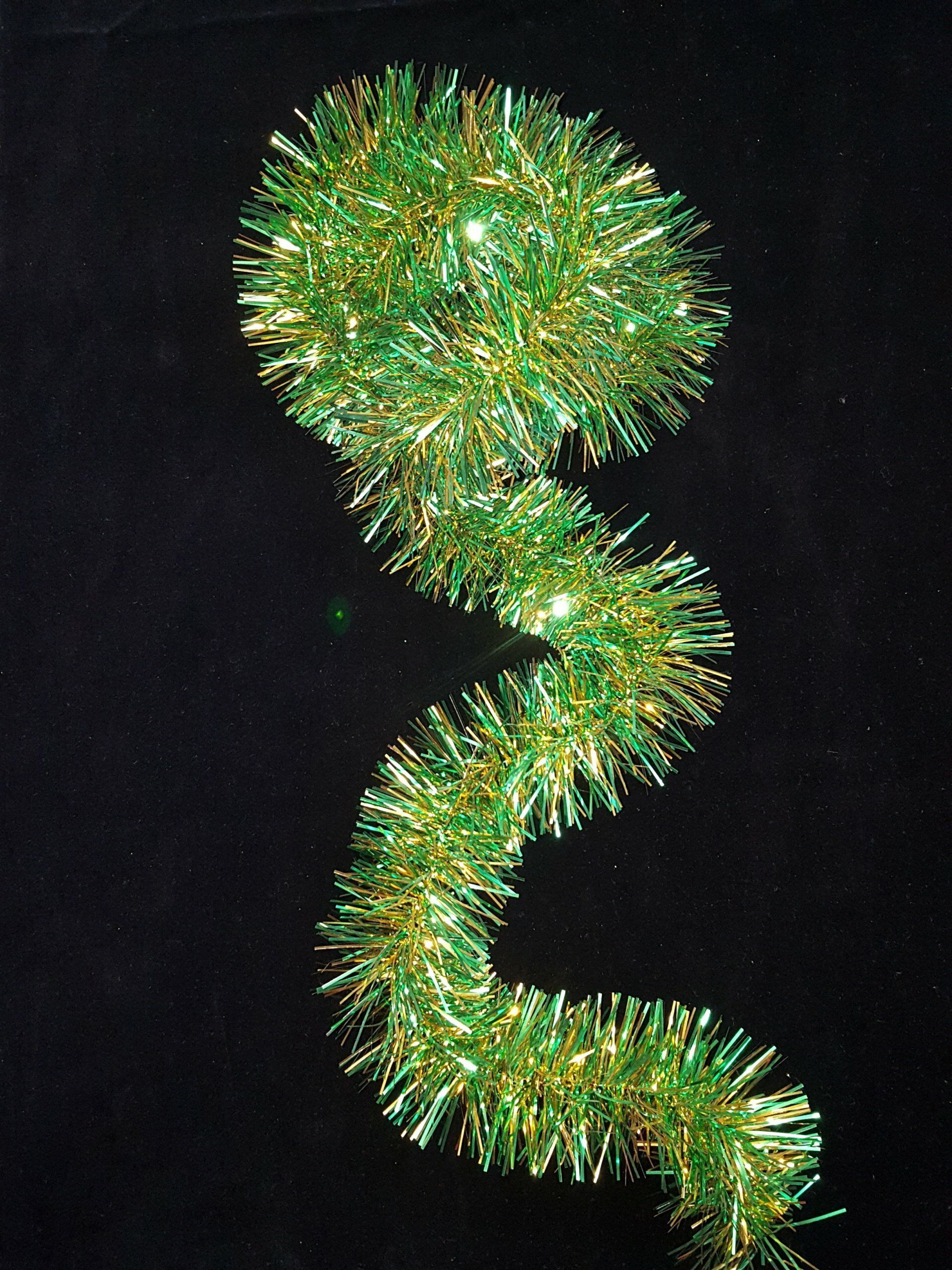 Guirnalda de oropel verde con forma de espiral ondulada sobre un fondo negro.