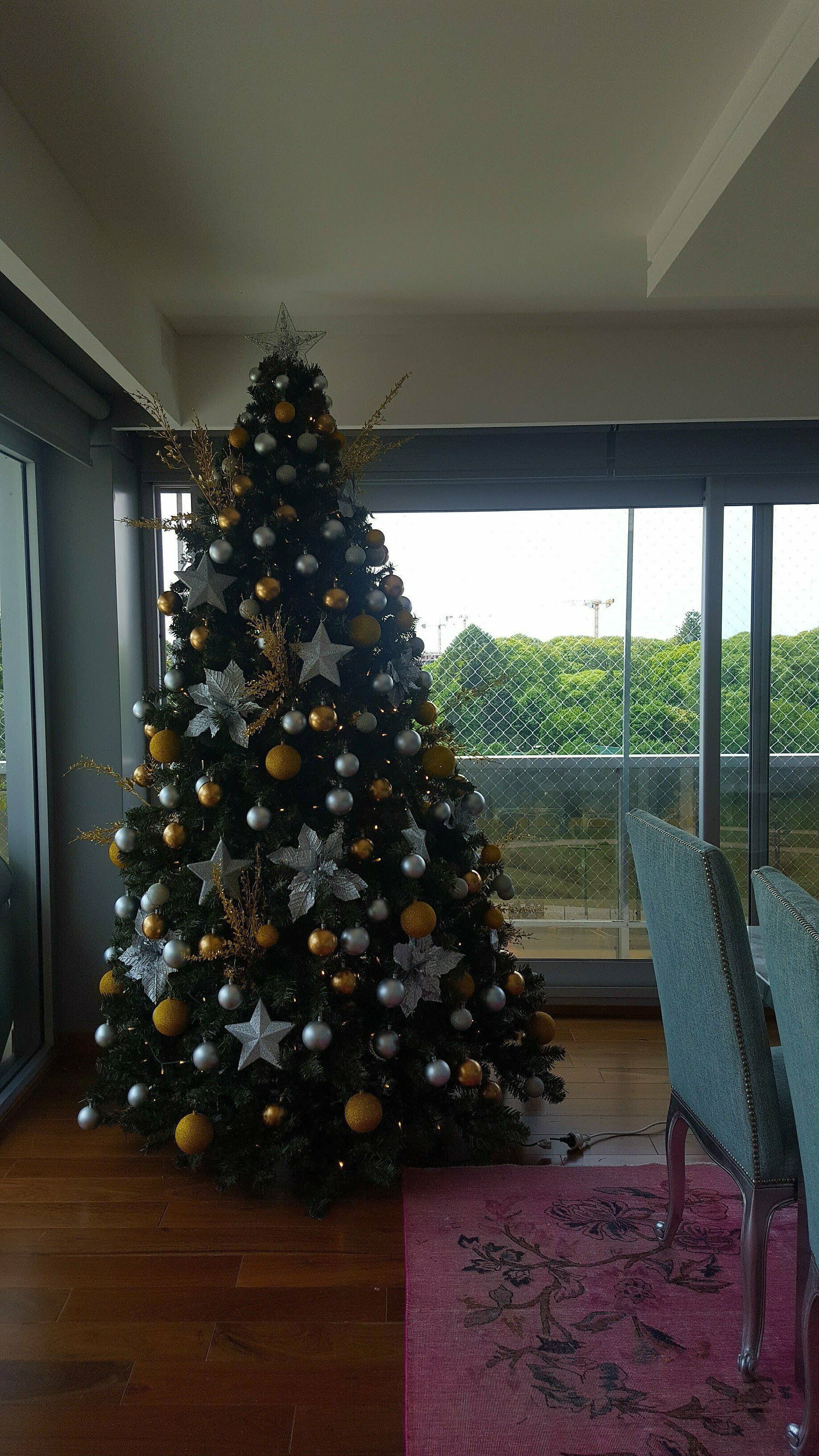 Árbol de Navidad decorado en un luminoso salón junto a puertas correderas de cristal.
