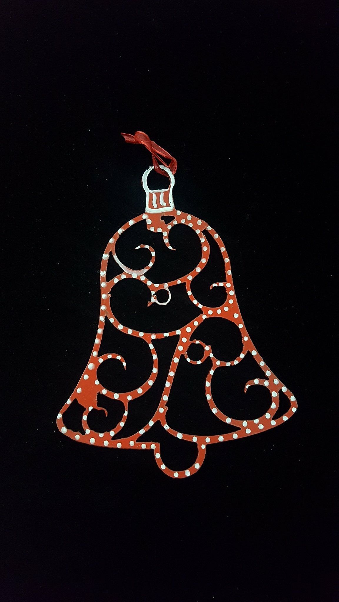 Contorno decorativo de una campana roja y blanca sobre un fondo negro, con una estrella en la parte superior.