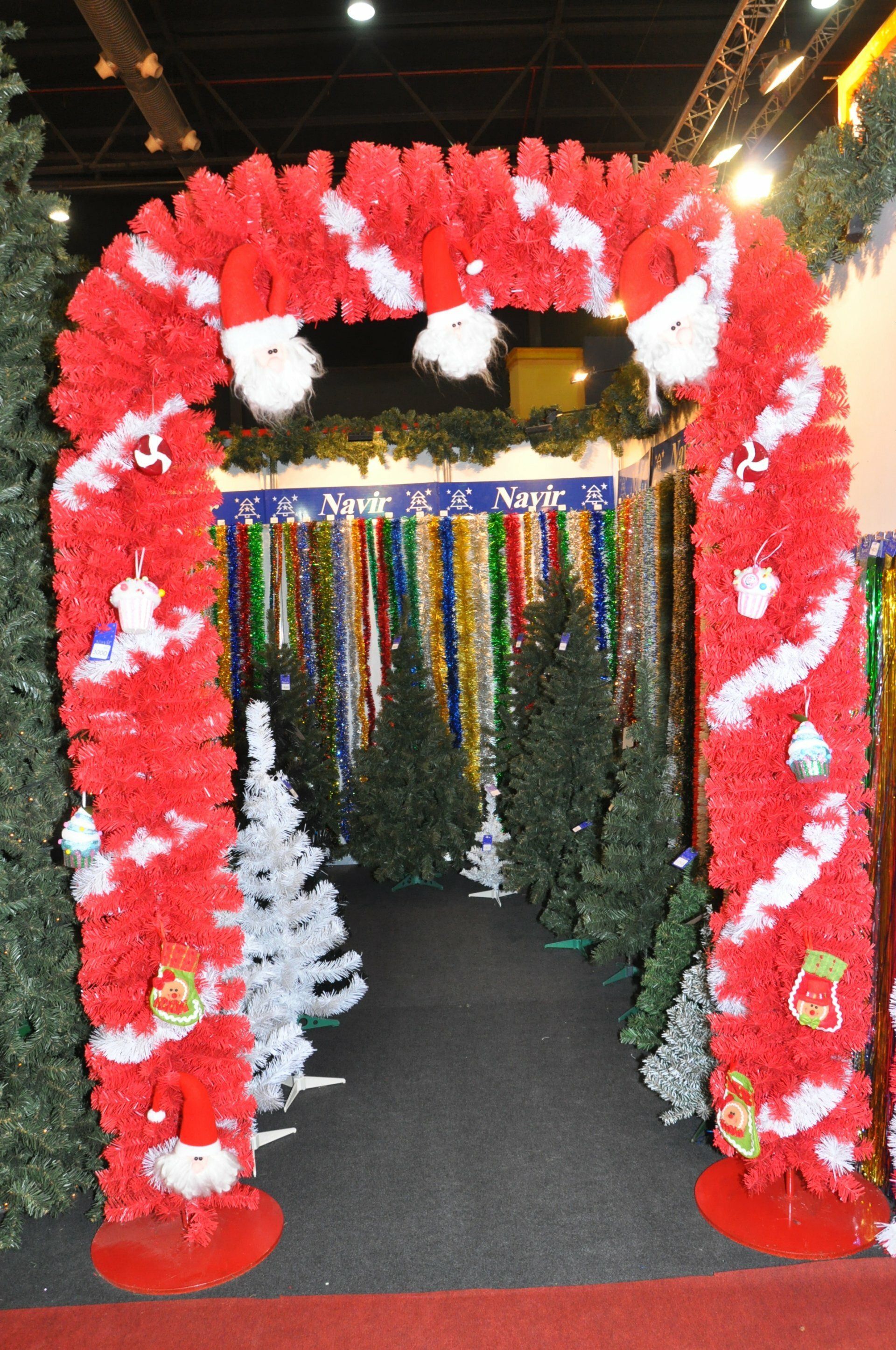 Arco de entrada floral rojo y blanco con serpentinas multicolores colgantes en un espacio interior decorado.