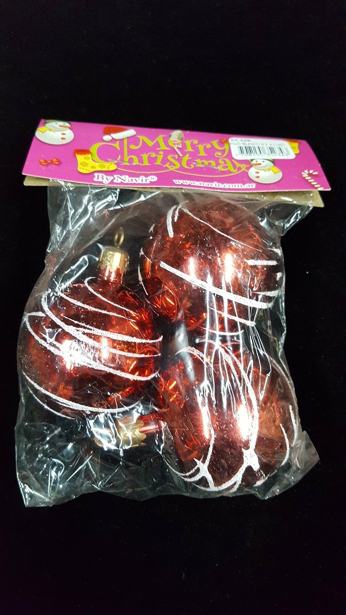 Bolsa de plástico transparente con adornos navideños rojos brillantes sobre una tarjeta con encabezado rosa.