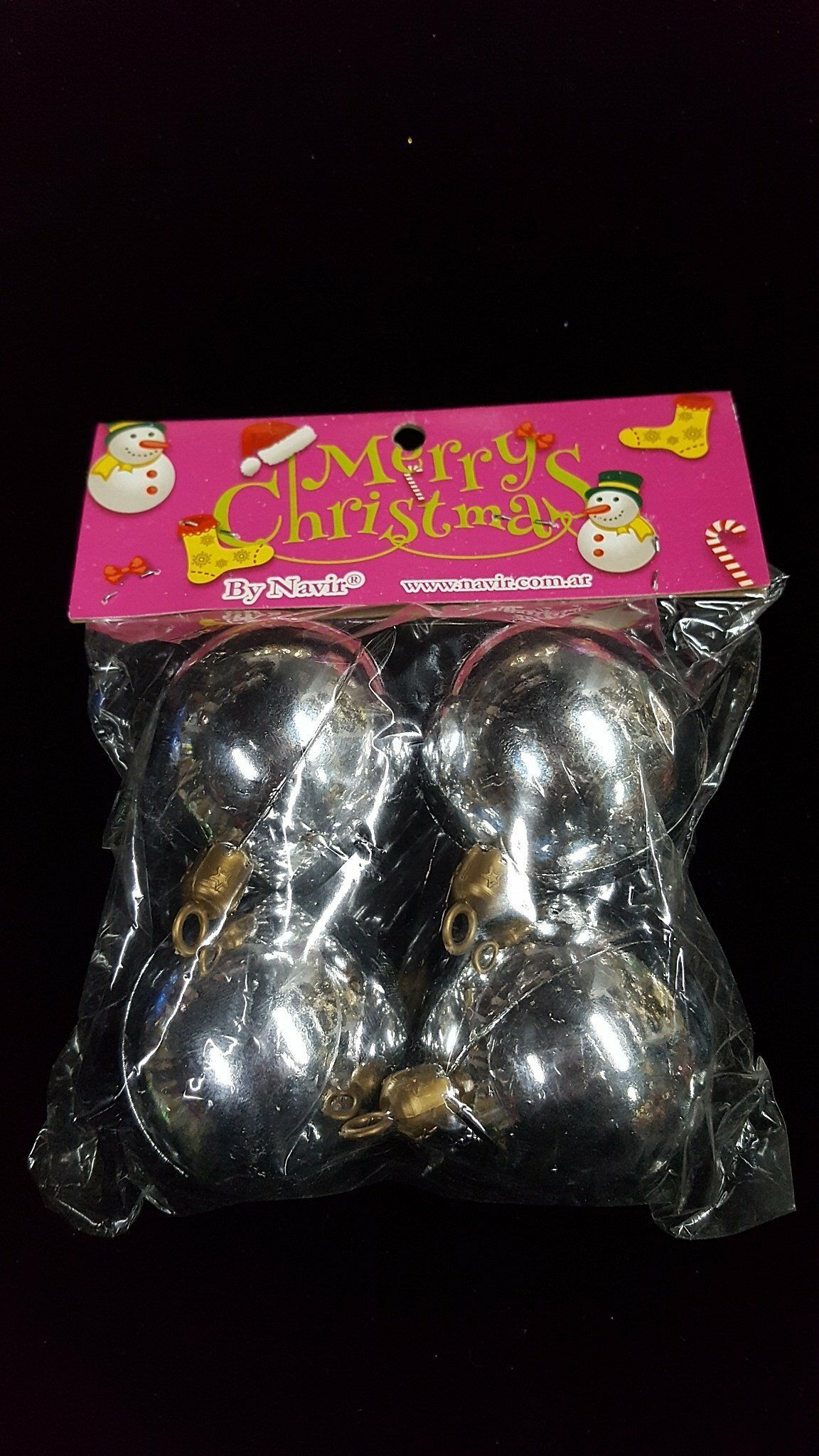 Bolsa de regalo rosa de Navidad que contiene adornos plateados brillantes en un embalaje de plástico transparente.