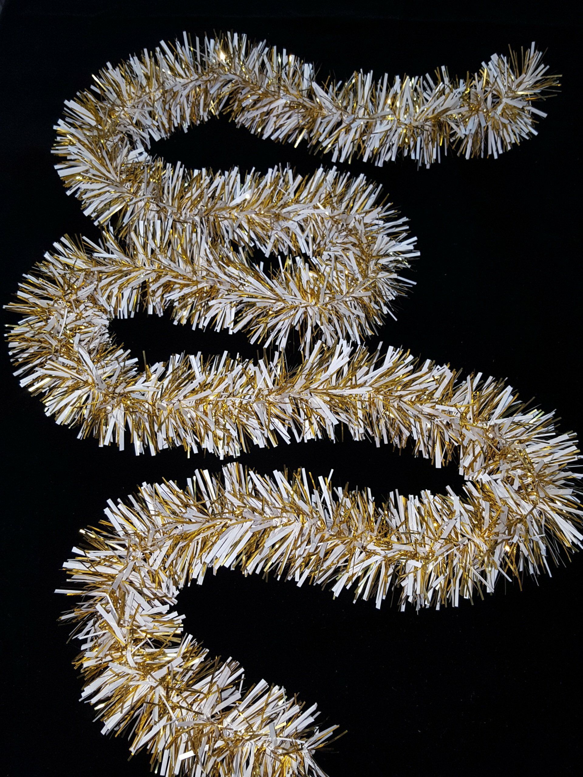 Guirnalda de oropel dorado enrollada en zigzag suelto sobre un fondo negro.