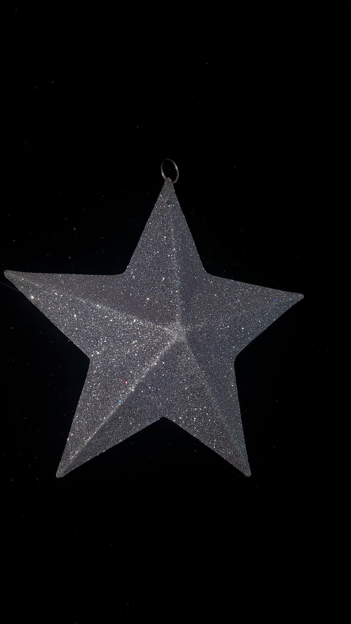 Adorno de estrella plateada brillante colgando sobre un fondo negro