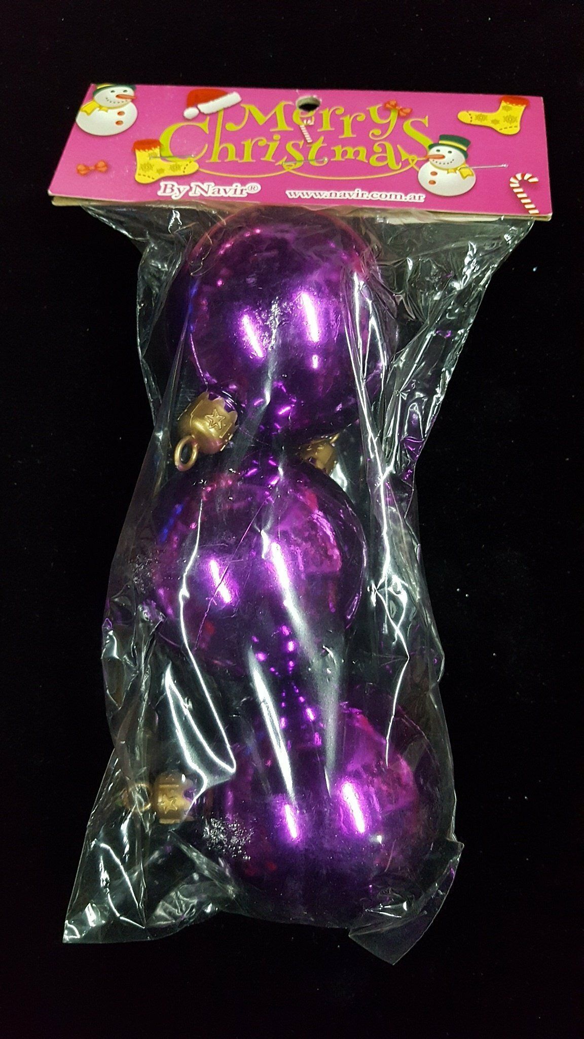 Adorno navideño morado en un embalaje transparente con tarjeta de cabecera rosa sobre fondo negro.