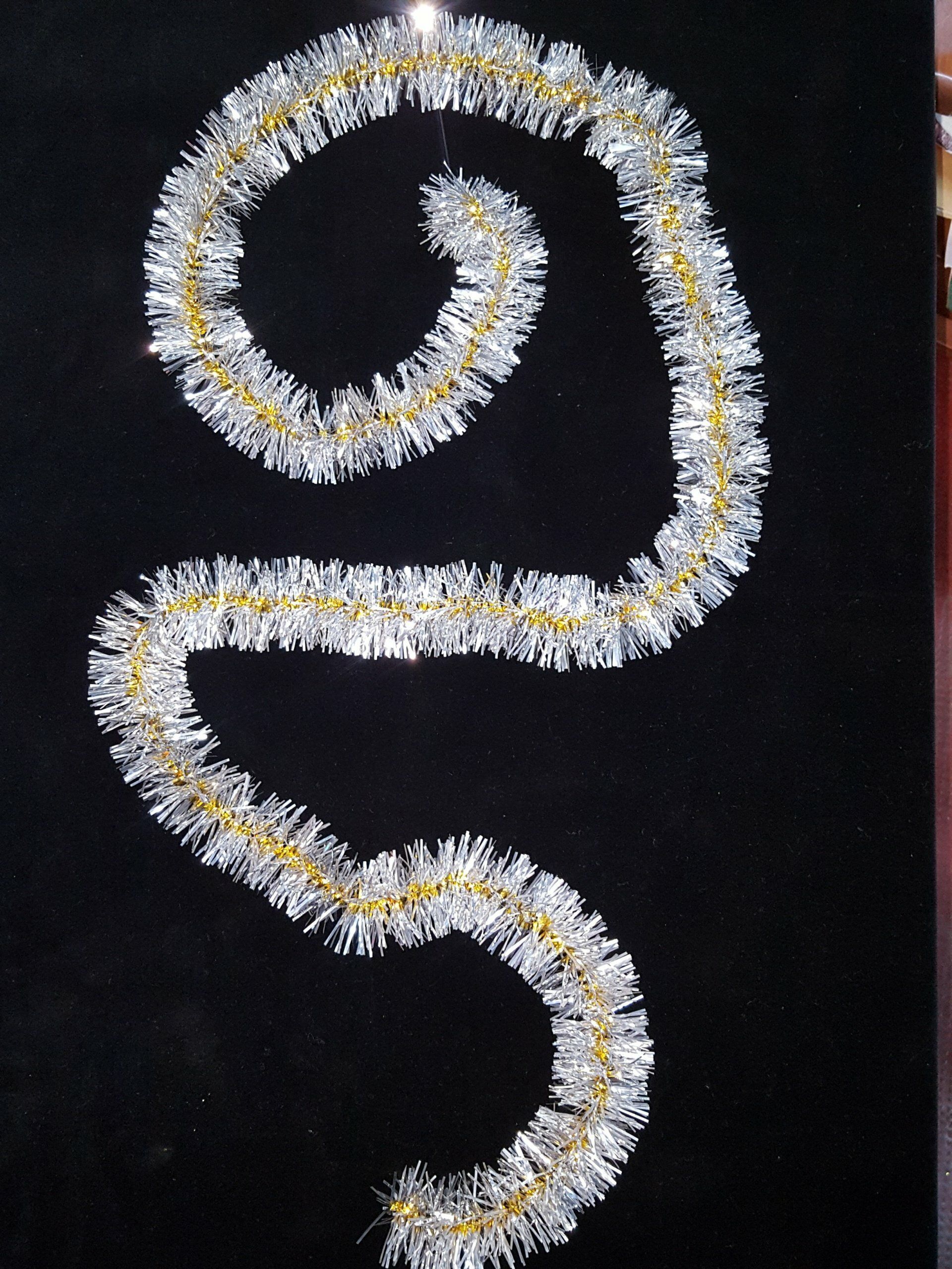 Guirnaldas blancas y amarillas dispuestas en espiral sobre un fondo negro.