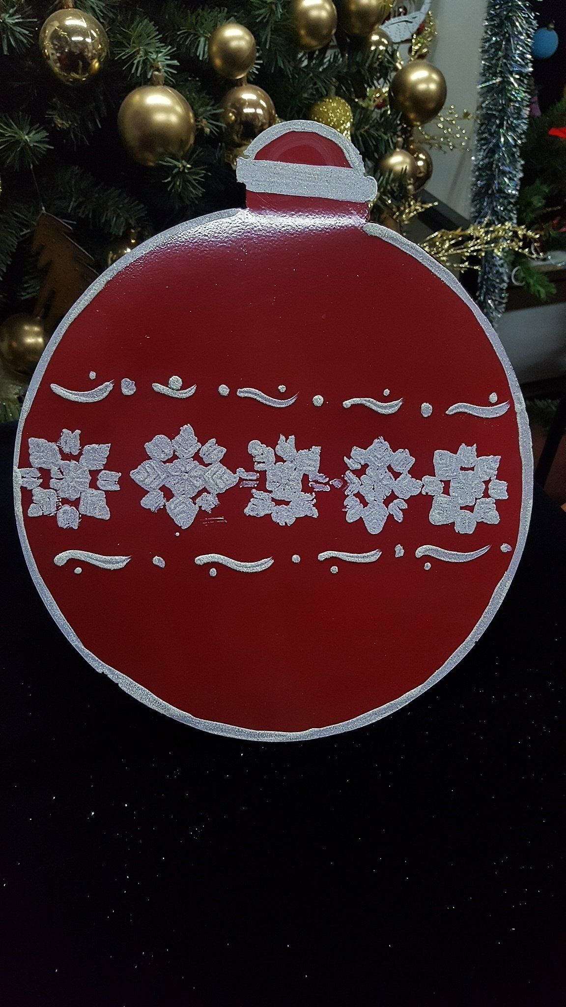 Adorno navideño rojo con estampado de copos de nieve blancos colgando de un árbol decorado.