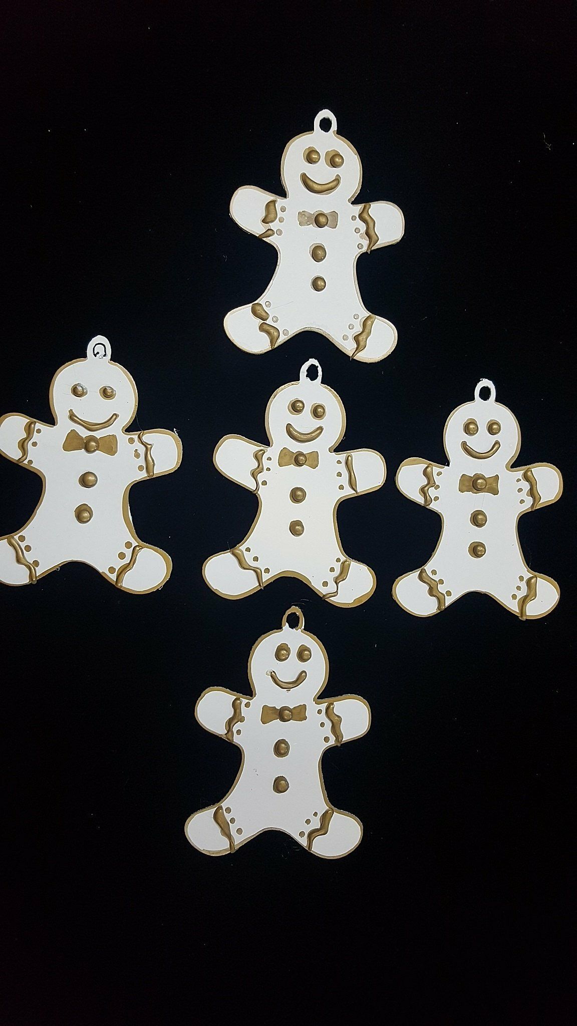 Cinco galletas de jengibre sonrientes sobre un fondo negro, dispuestas en un grupo suelto.