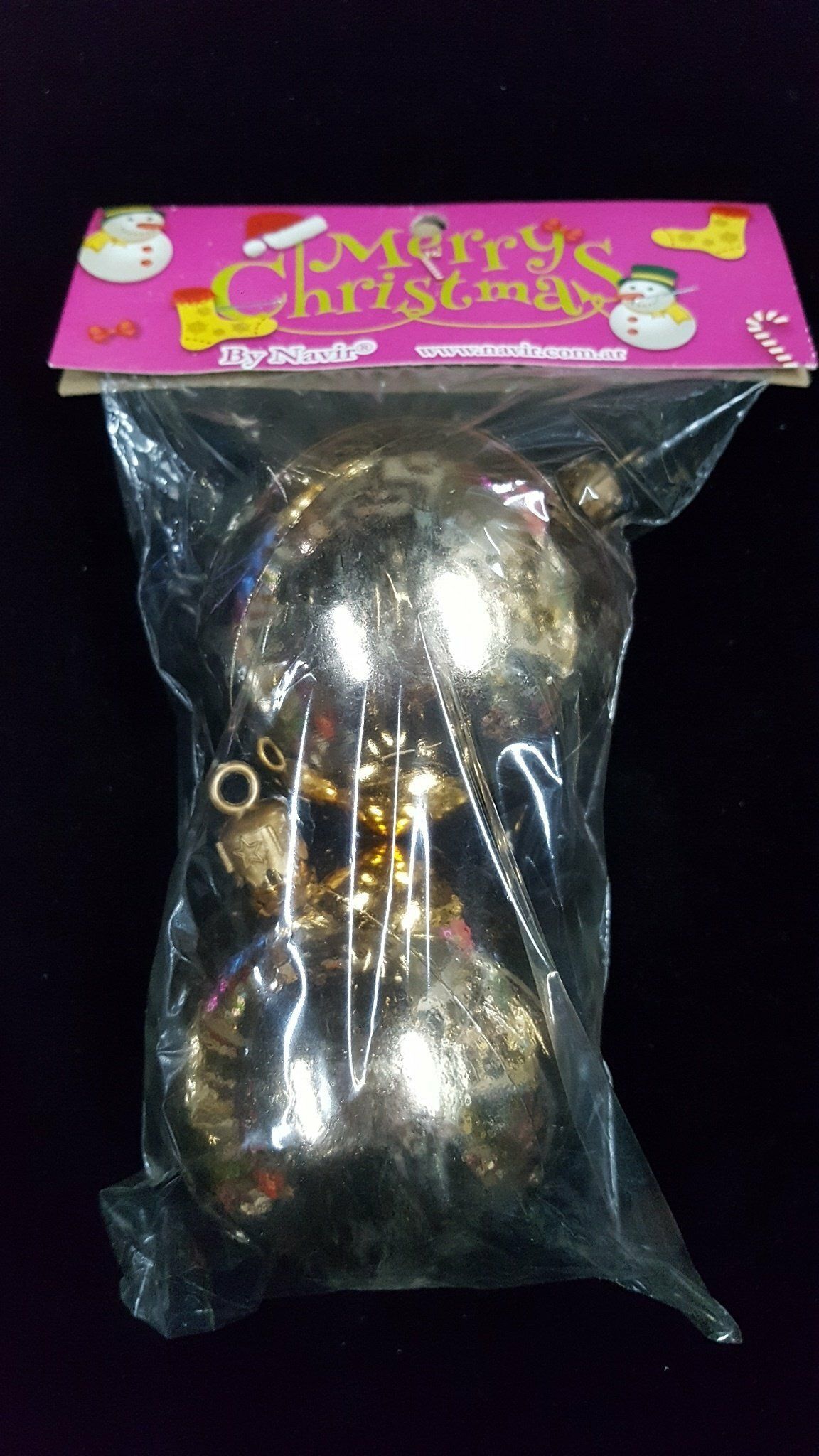 Bolsa de plástico transparente con adornos navideños brillantes y una tarjeta navideña rosa.
