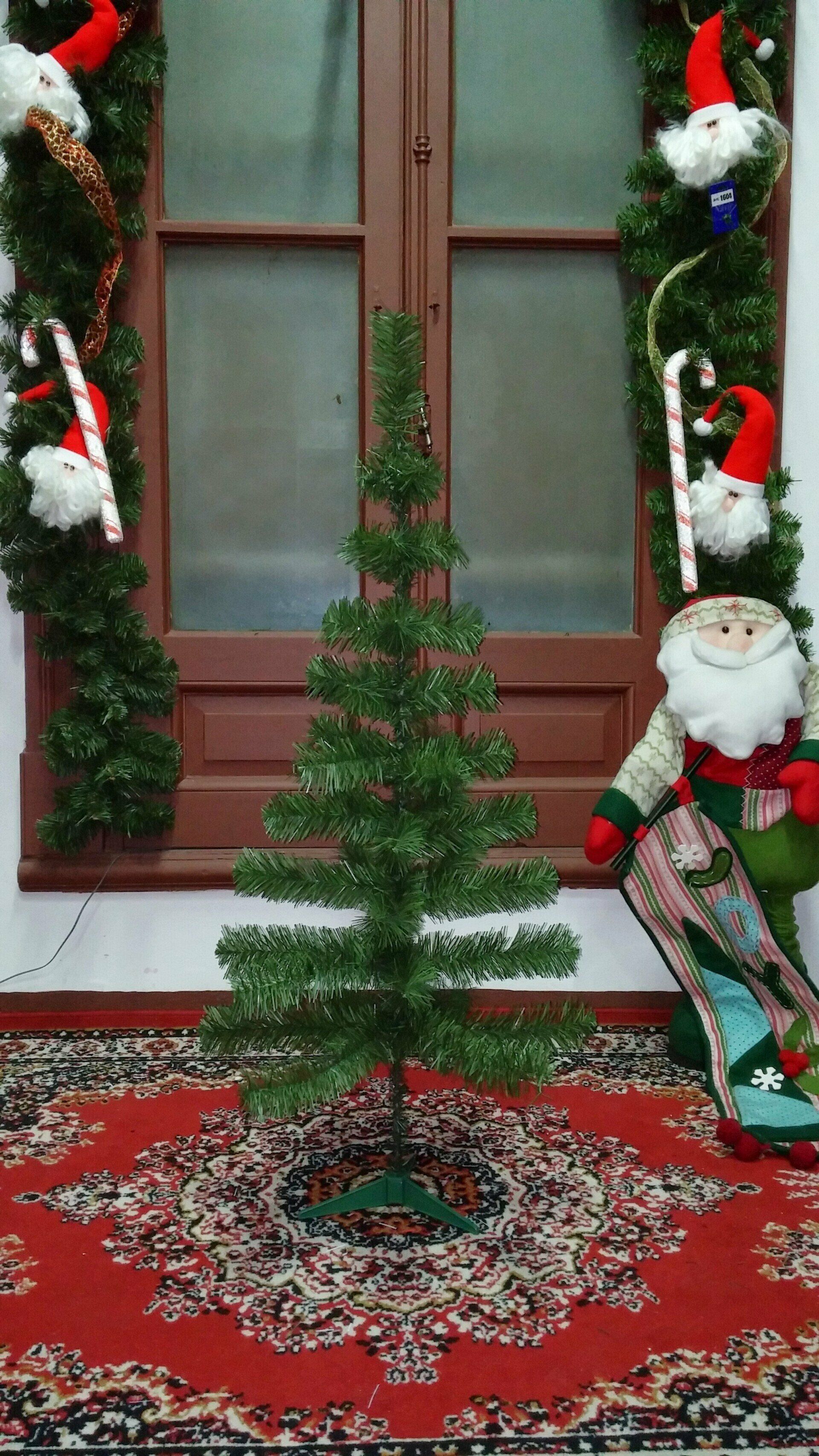 Entrada decorada para Navidad con guirnaldas, ositos de peluche y un pequeño árbol sobre una alfombra roja estampada.