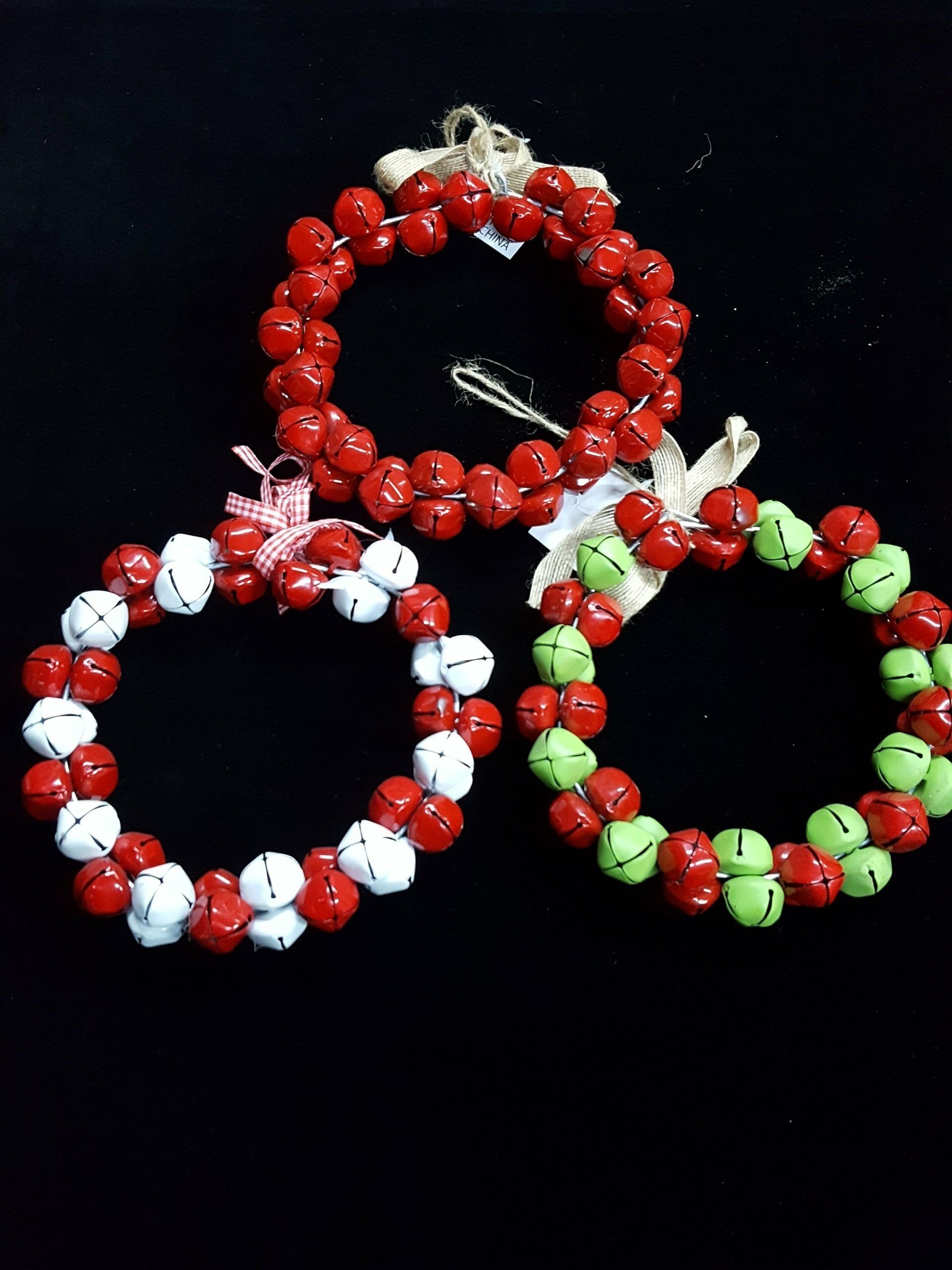 Tres aros de pulsera de cuentas en rojo, blanco y verde sobre un fondo negro.