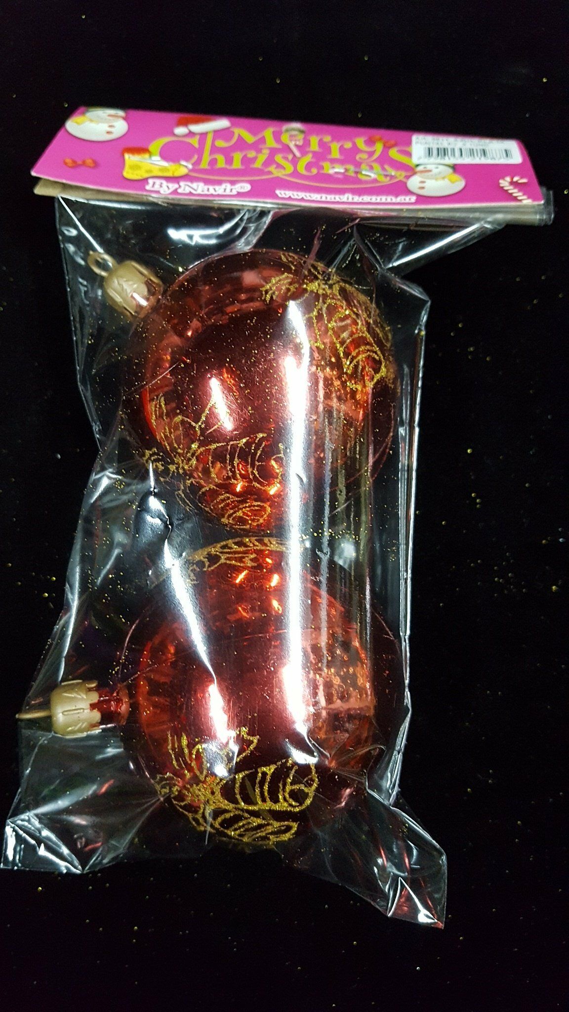 Cuerno o varita decorativa roja y dorada empaquetada en plástico transparente con tarjeta de cabecera rosa.