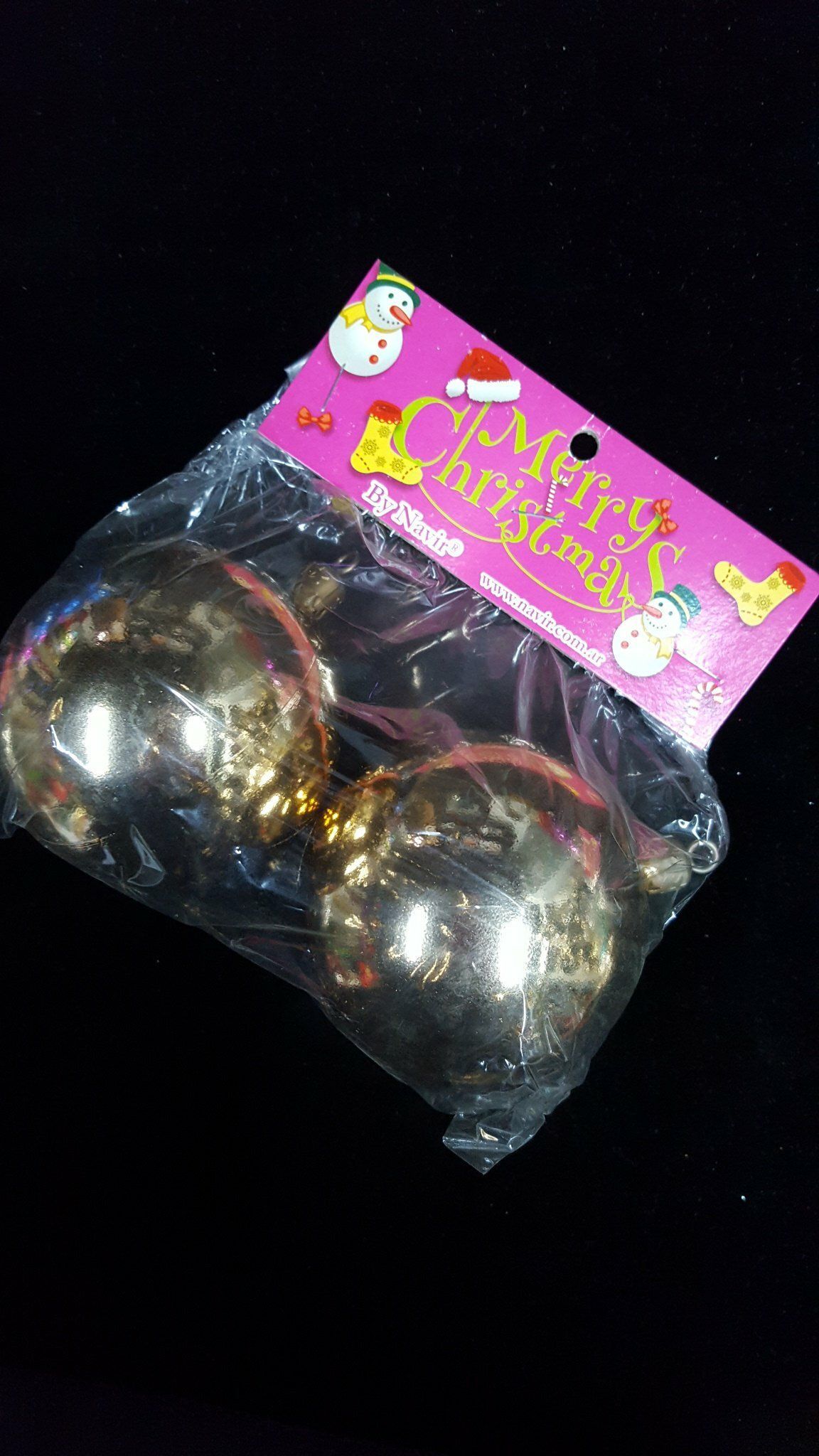 Dos adornos navideños plateados en un envase de plástico transparente con una etiqueta navideña rosa.