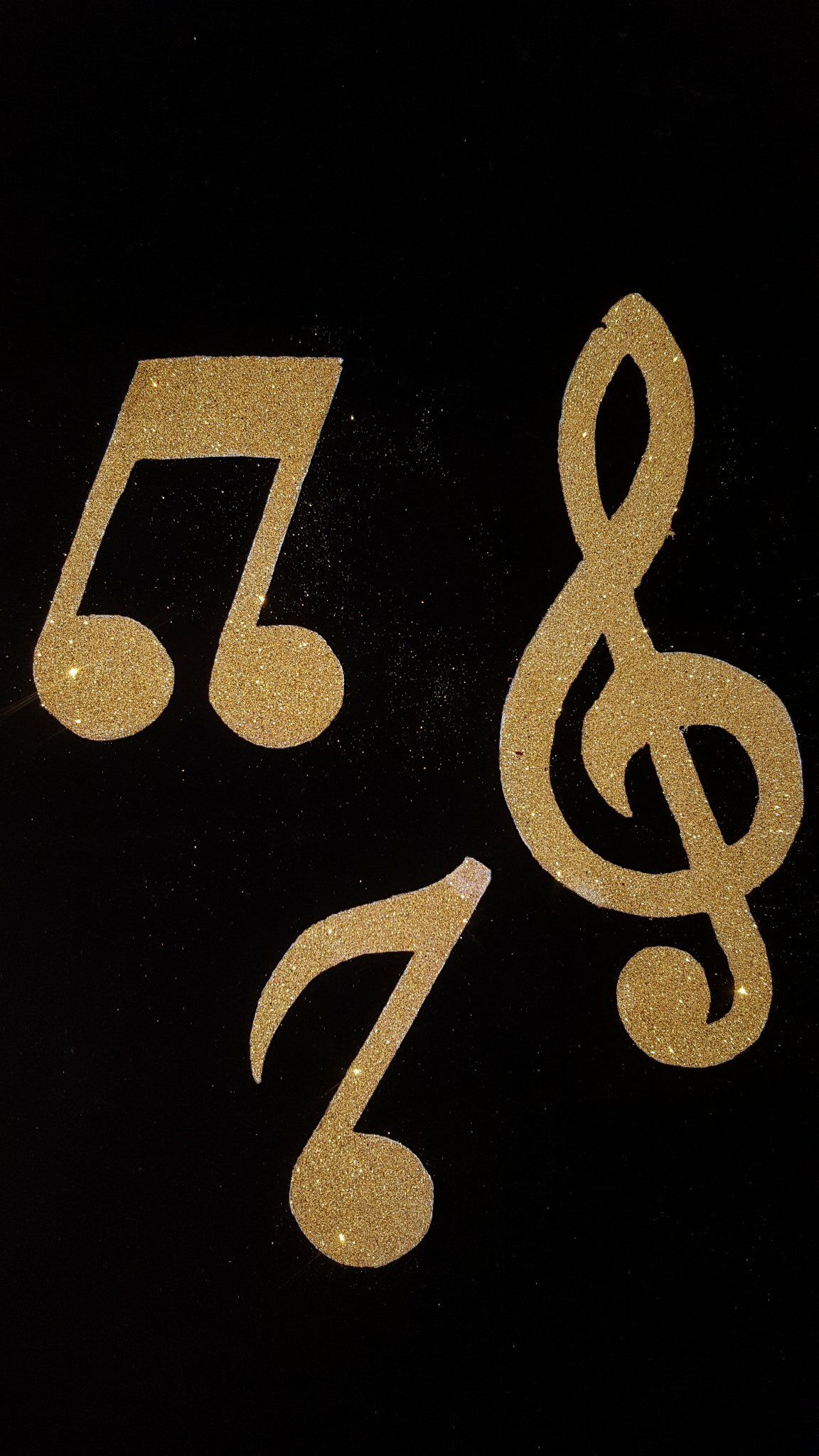 Notas musicales doradas y una clave de sol sobre un fondo negro.
