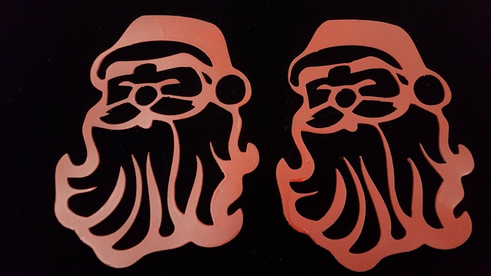 Dos rostros estilizados de Papá Noel con contorno rojo sobre un fondo negro.