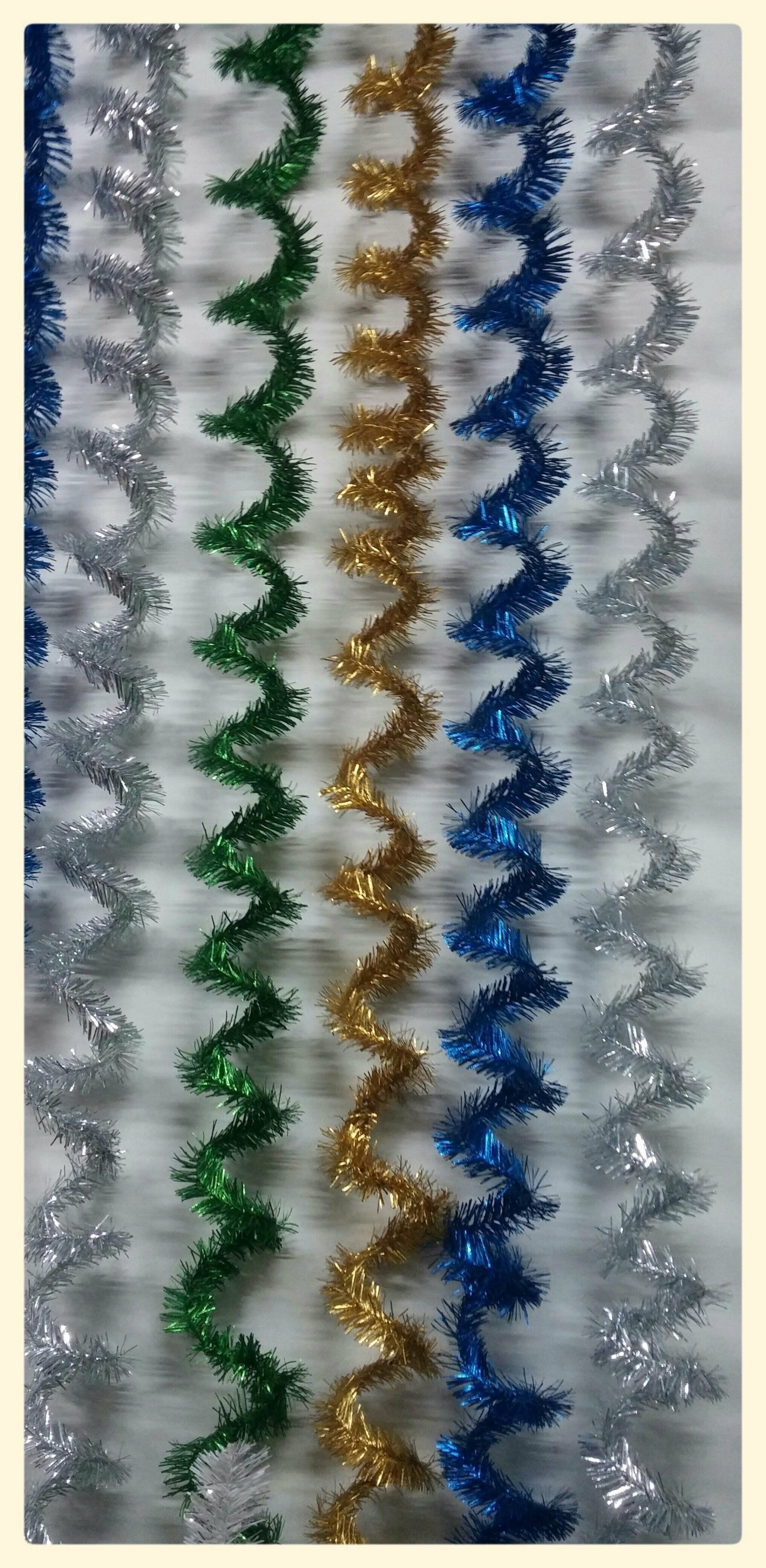 Hileras verticales de guirnaldas de oropel brillante en zigzag en verde, dorado, azul y plateado.