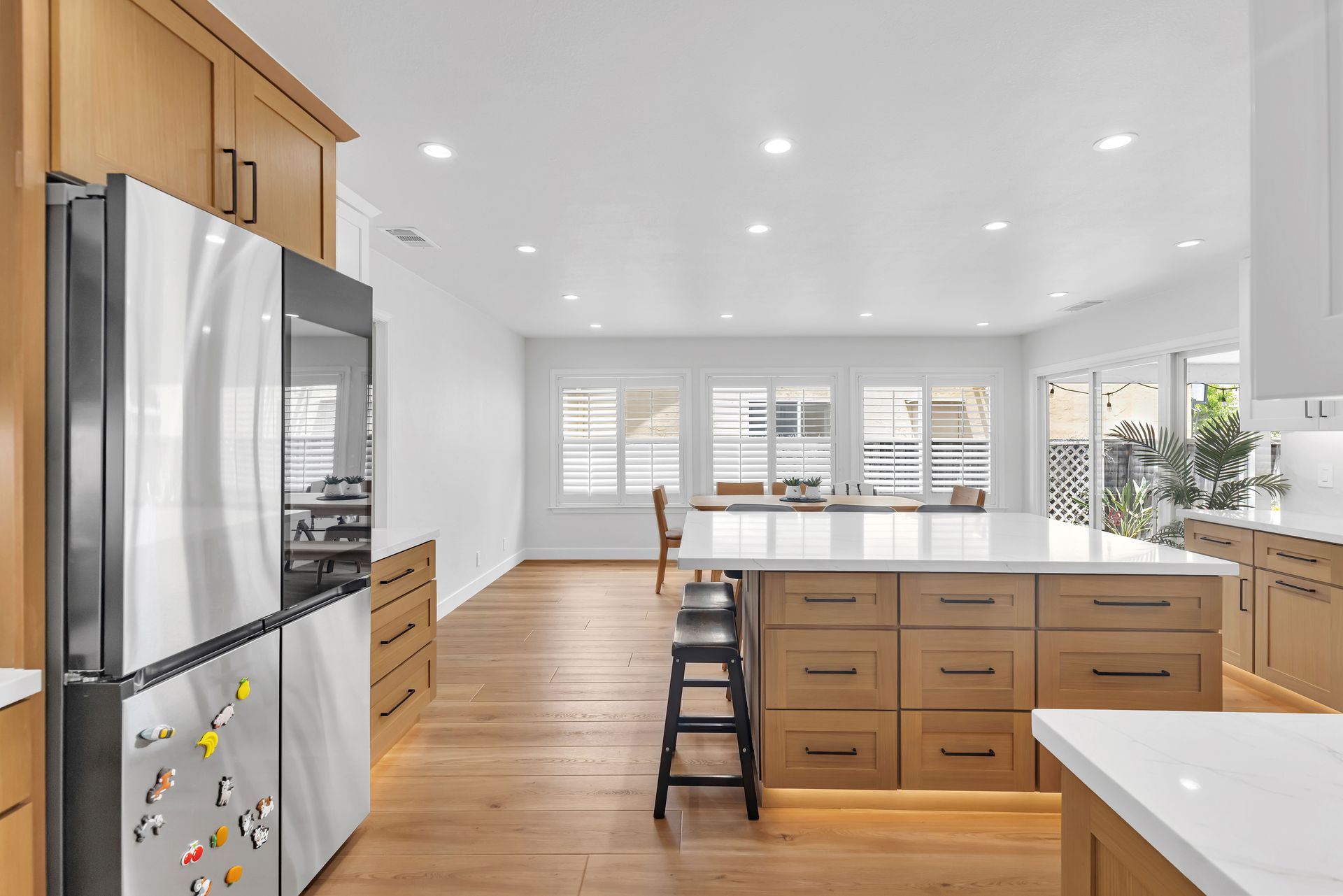 Modern kitchen with wooden cabinets, stainless steel refrigerator, and large island with seating.