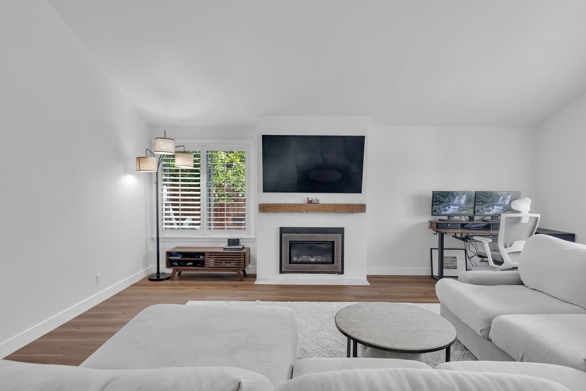 Living room with fireplace, TV, white walls, and a light-colored couch.