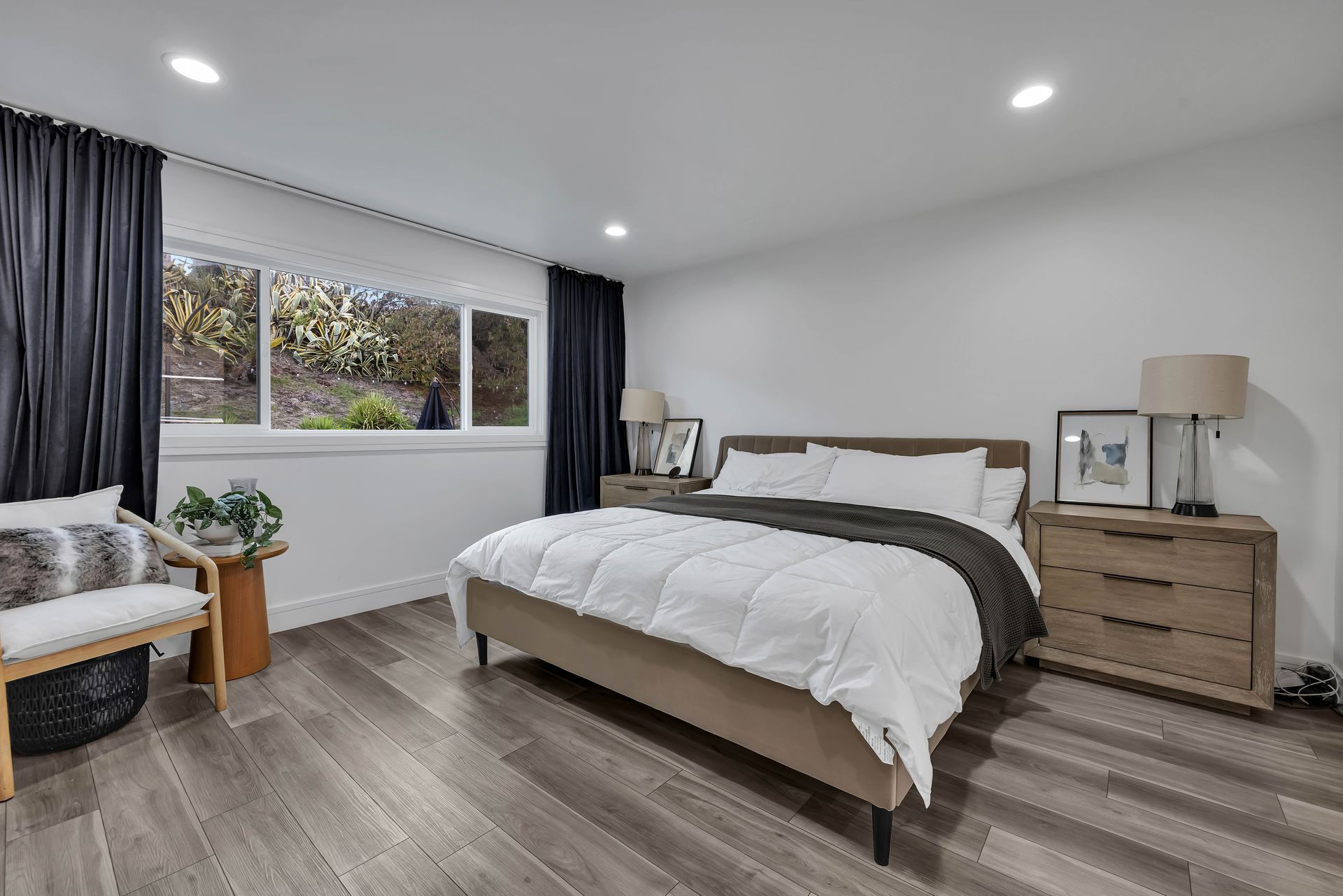 Bedroom with a bed, nightstands, chair, window, and dark curtains.