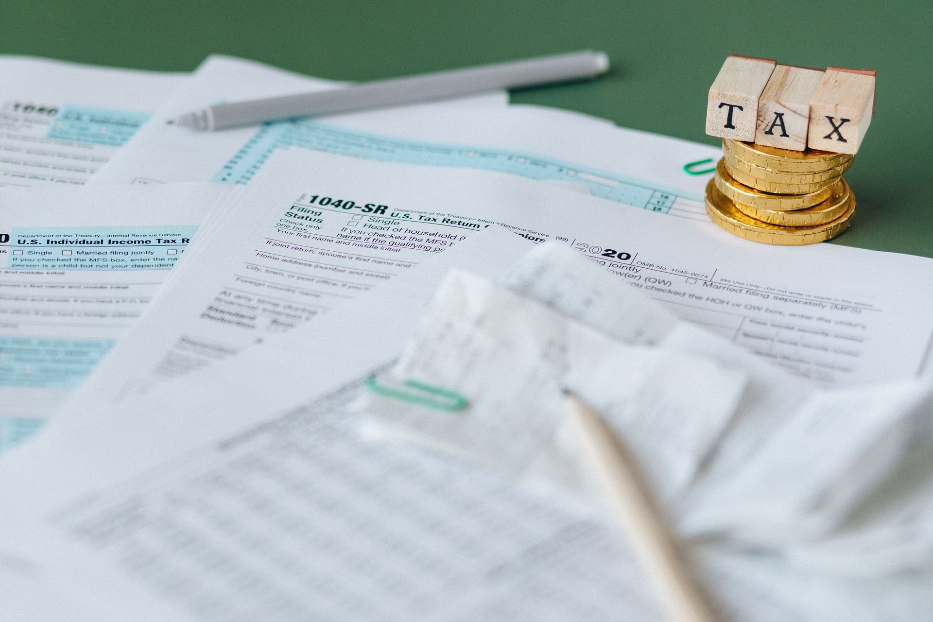 Tax forms and receipts on a desk with a gold coin jar labeled “TAX”