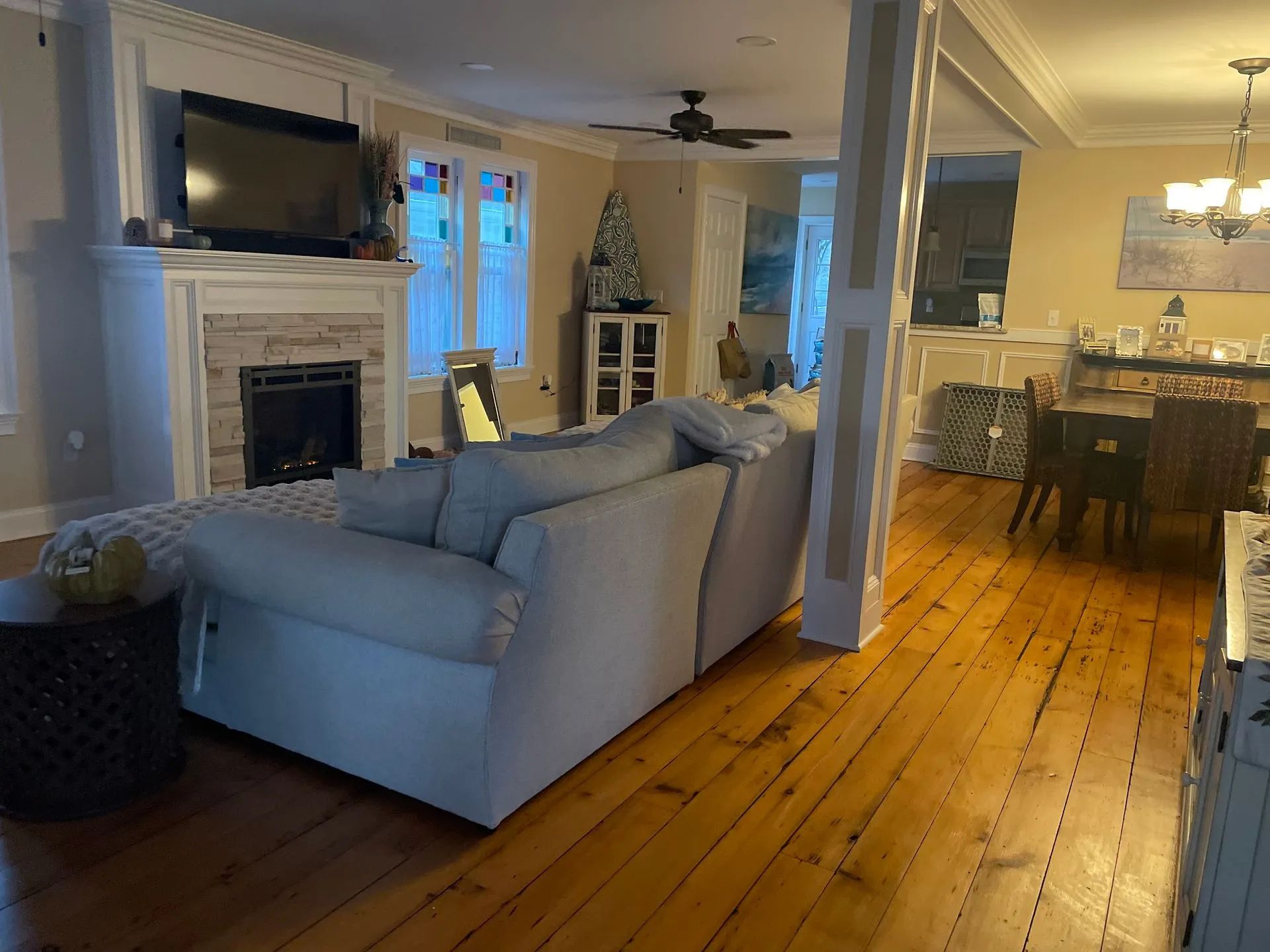 Bright living room with gray sectional, fireplace, TV, and dining area in the background.