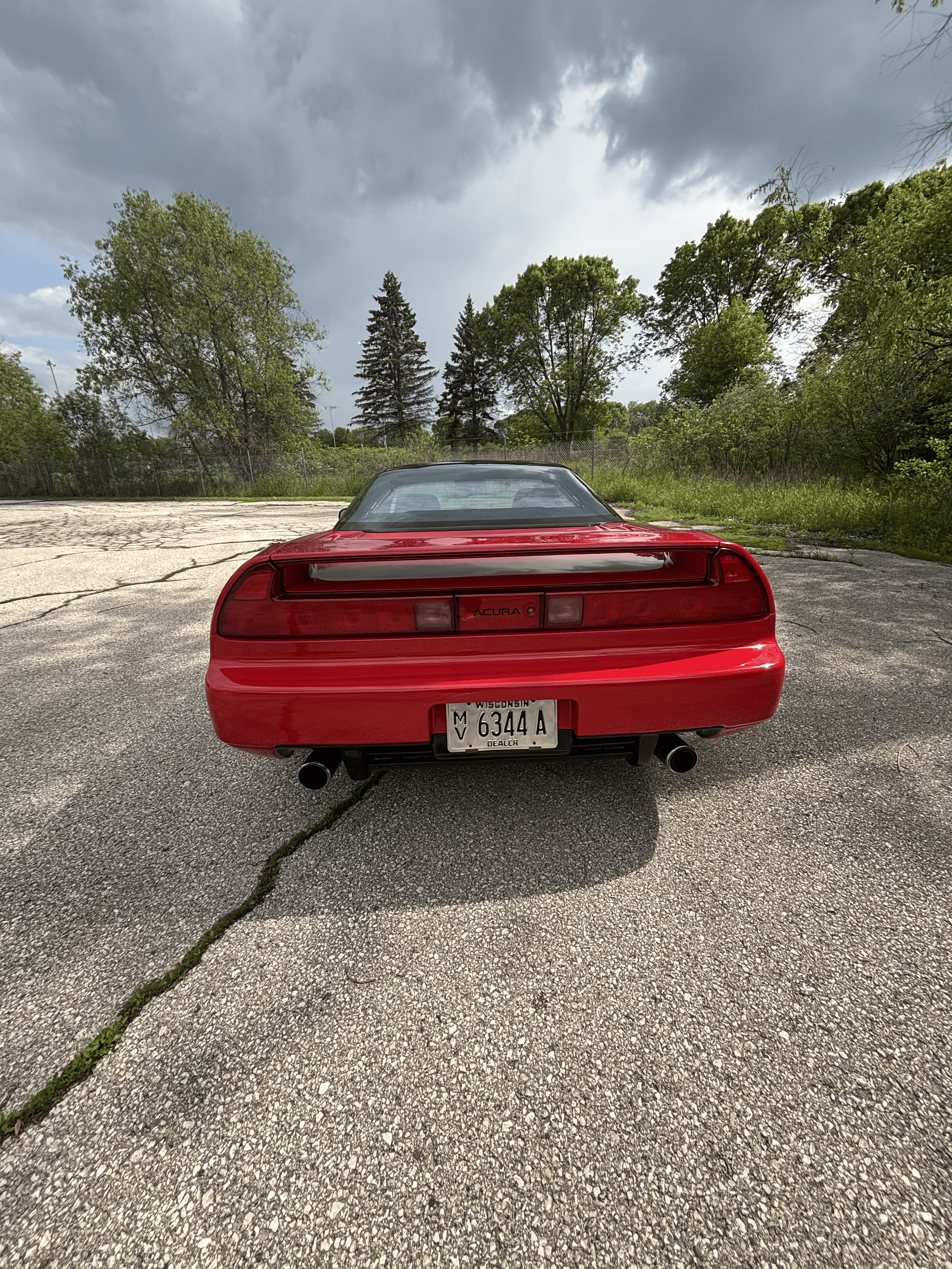 A red sports car is parked on a gravel road.