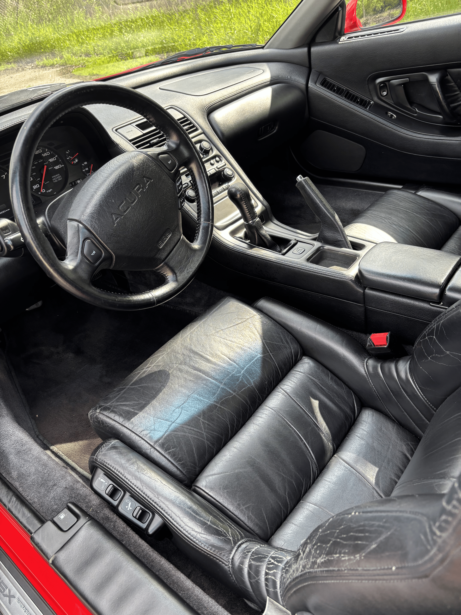 The interior of a red sports car with black leather seats and a steering wheel