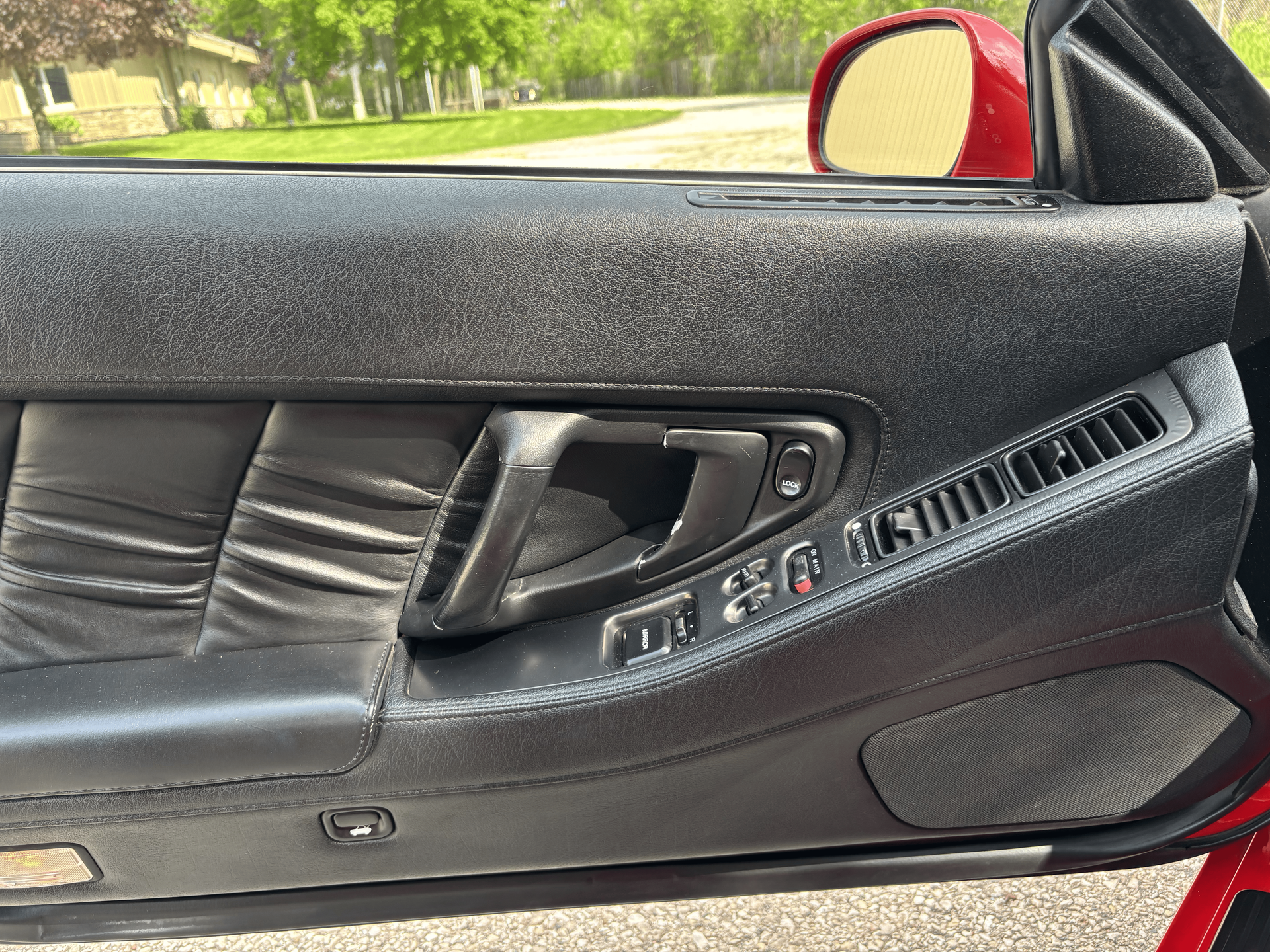 A close up of a car door with a red mirror