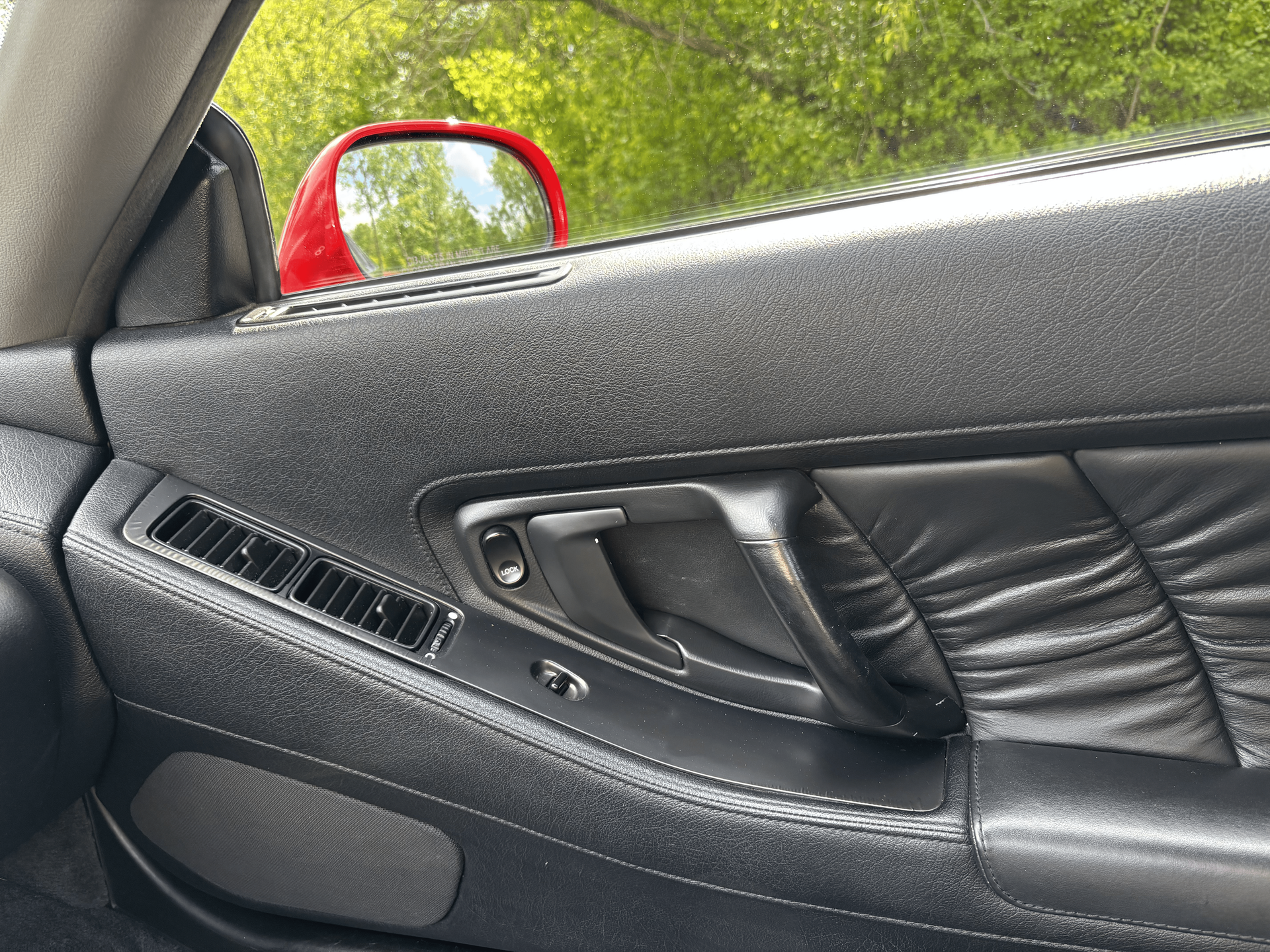 A close up of a car door with a red mirror