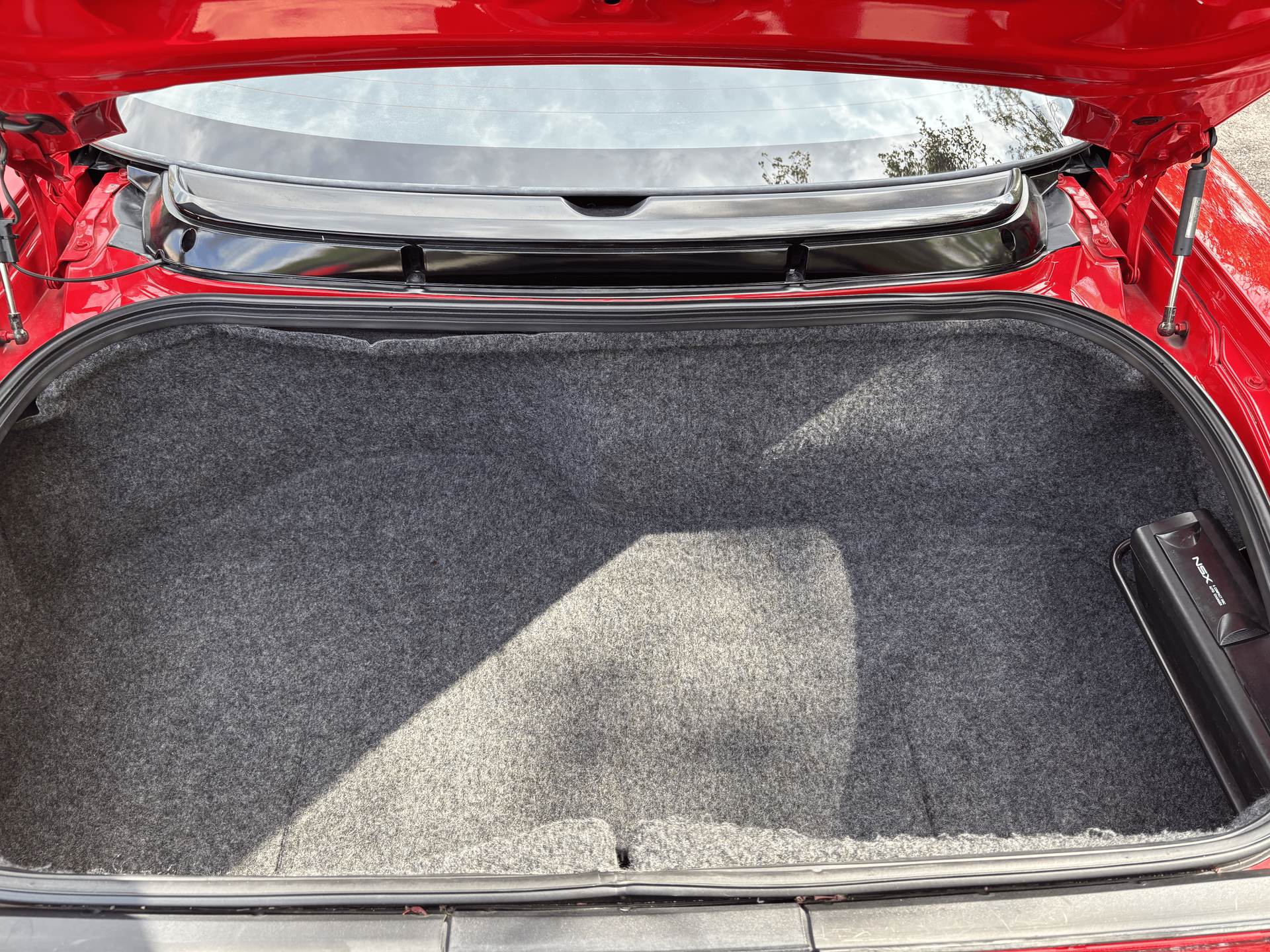 The trunk of a red car is open and empty.