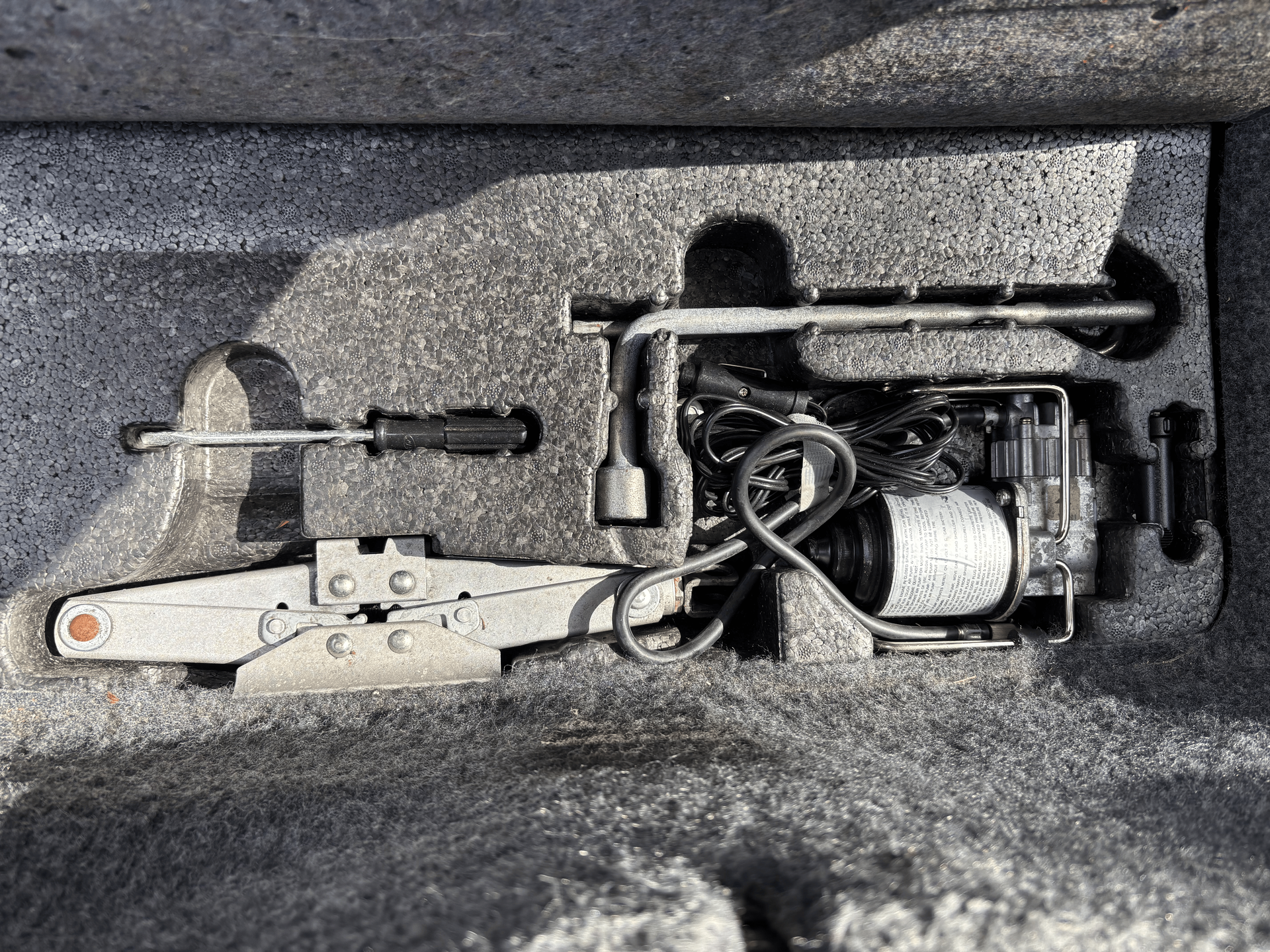 A car jack is sitting in the trunk of a car.