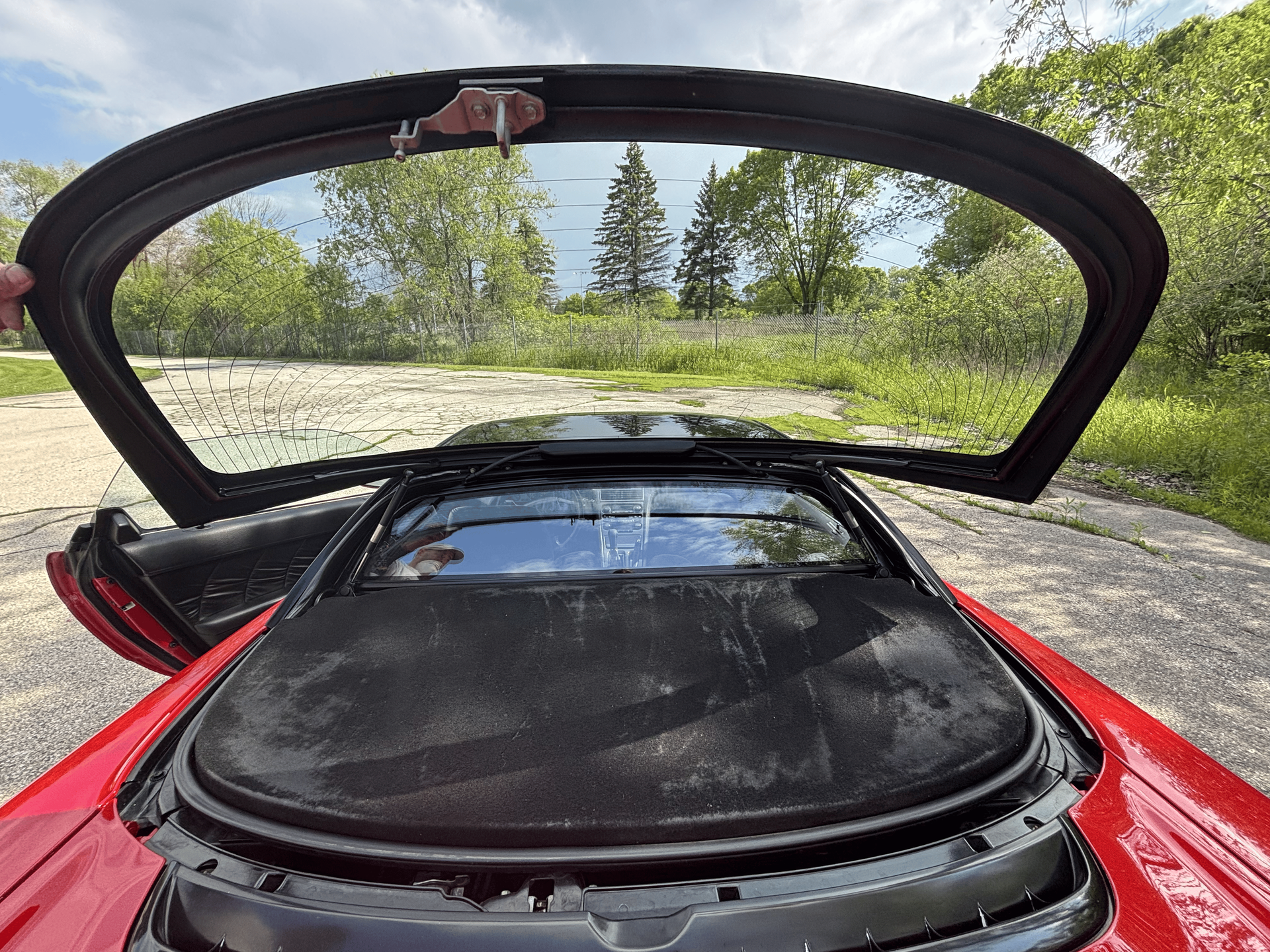 A person is opening the trunk of a red sports car.