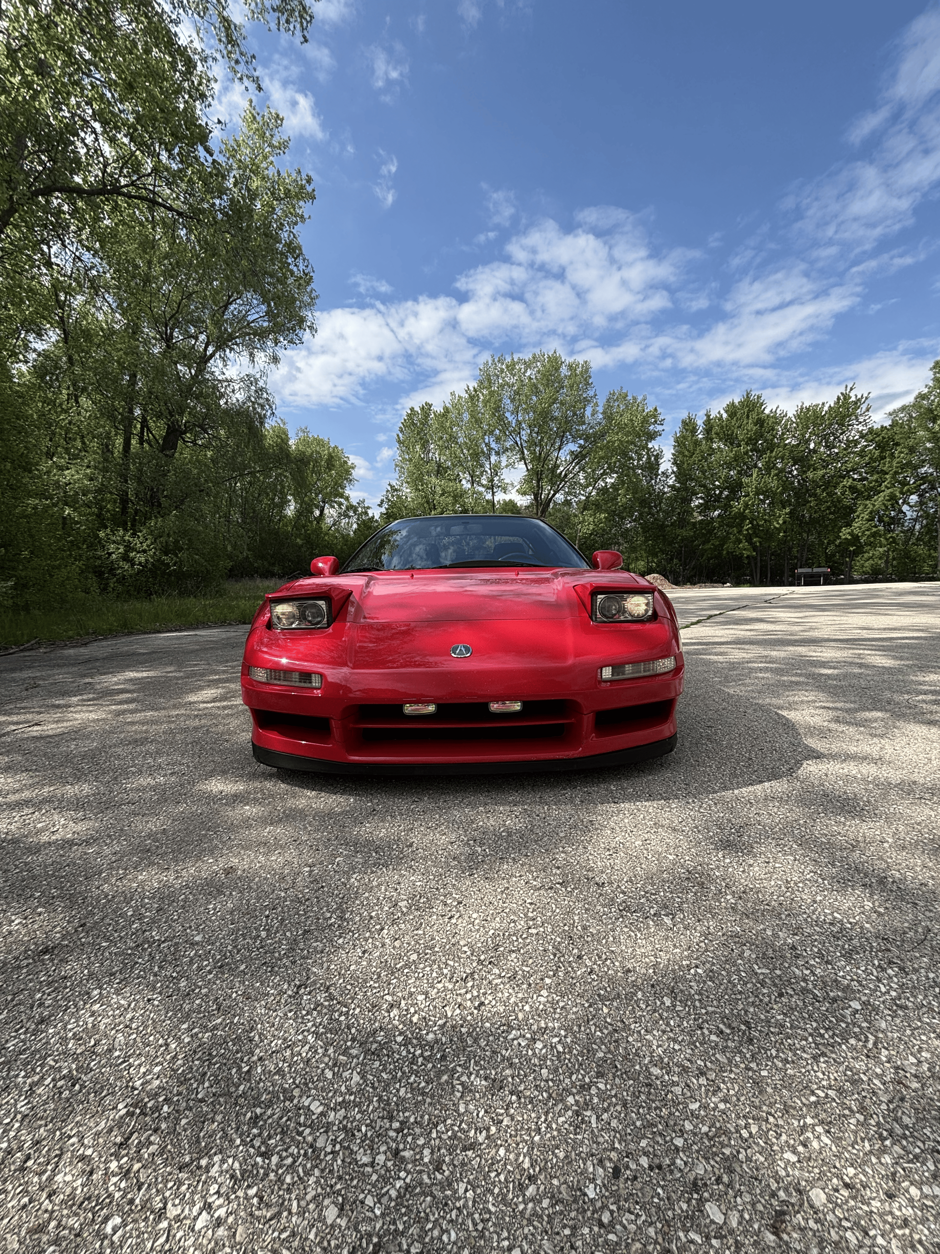 A red sports car is parked on a gravel road.