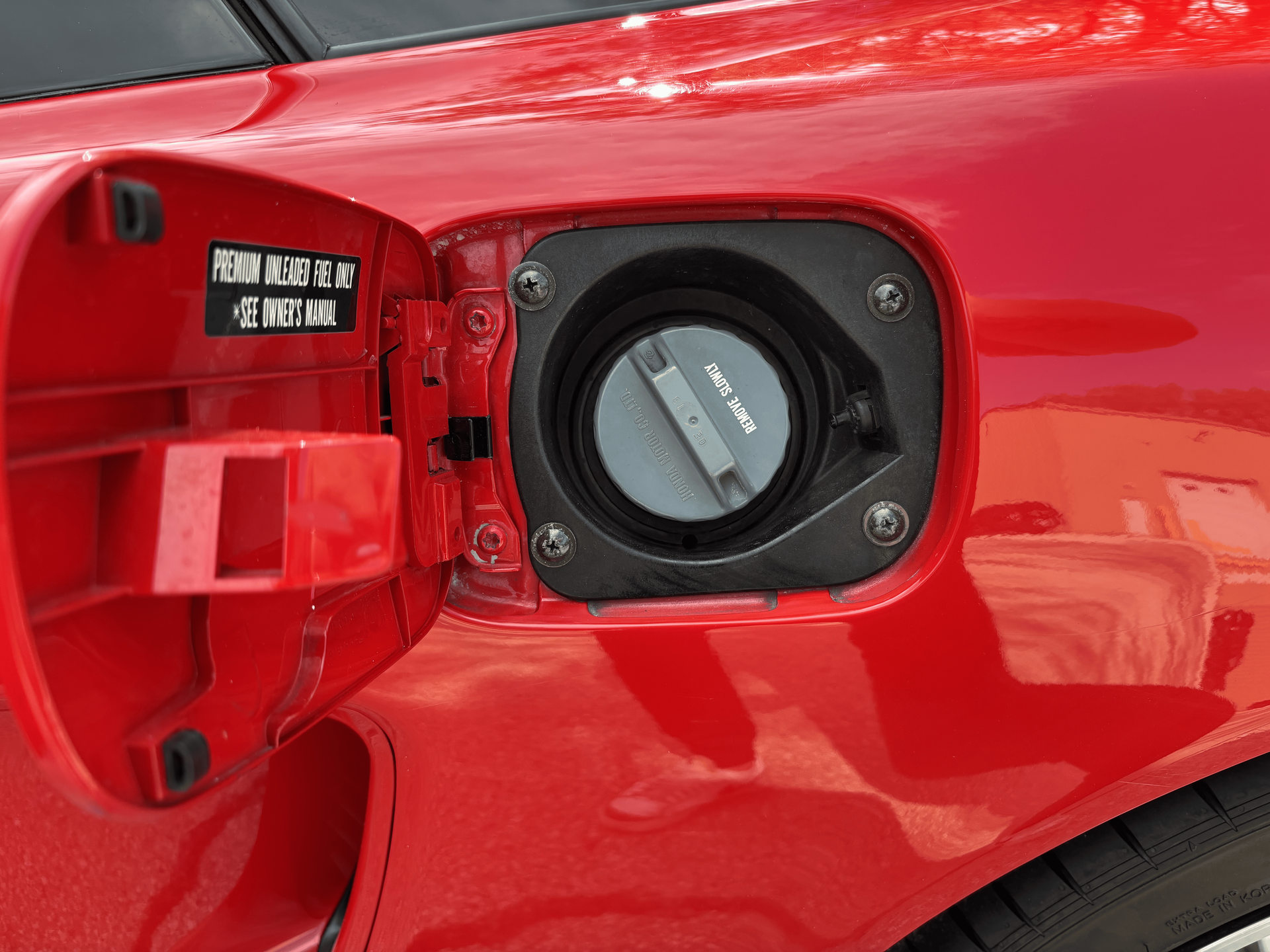 A close up of a red car with the fuel cap open.