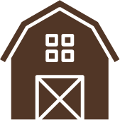 A brown barn with white squares on the windows and a white door.