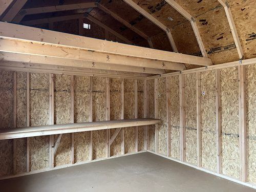 The inside of a wooden shed with shelves, and interior workbench