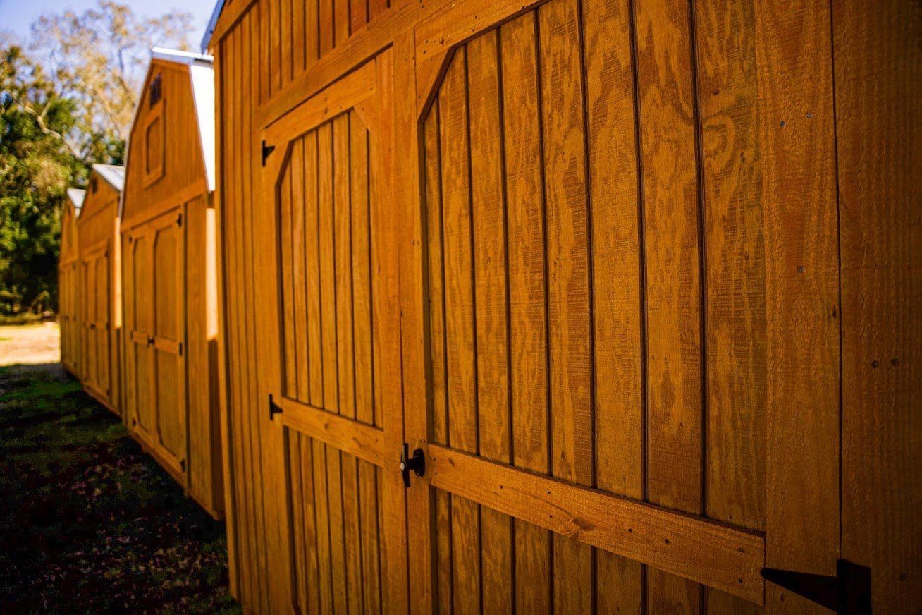 A row of wooden sheds are lined up next to each other.