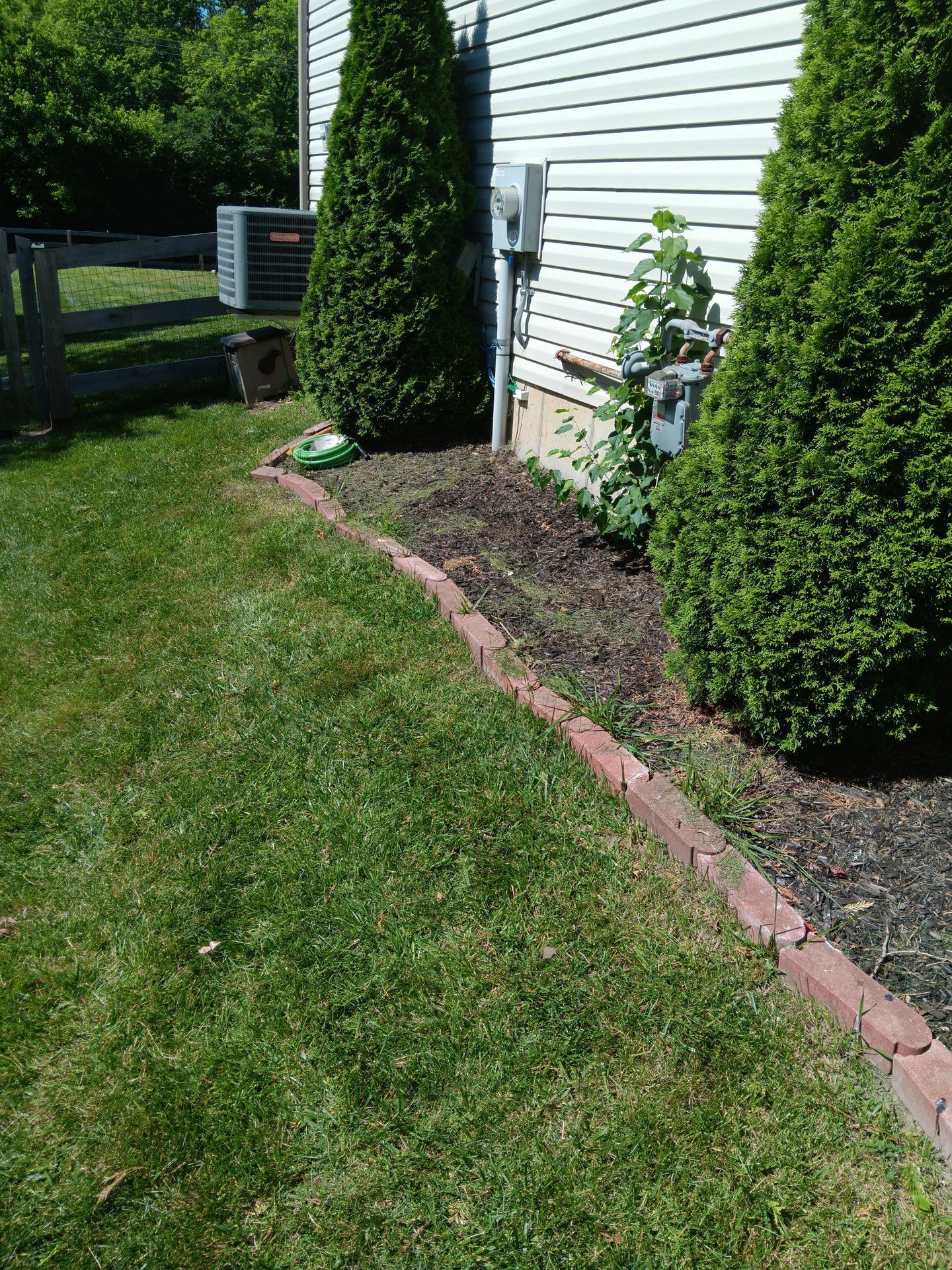 A lawn with a brick border and a white house in the background.