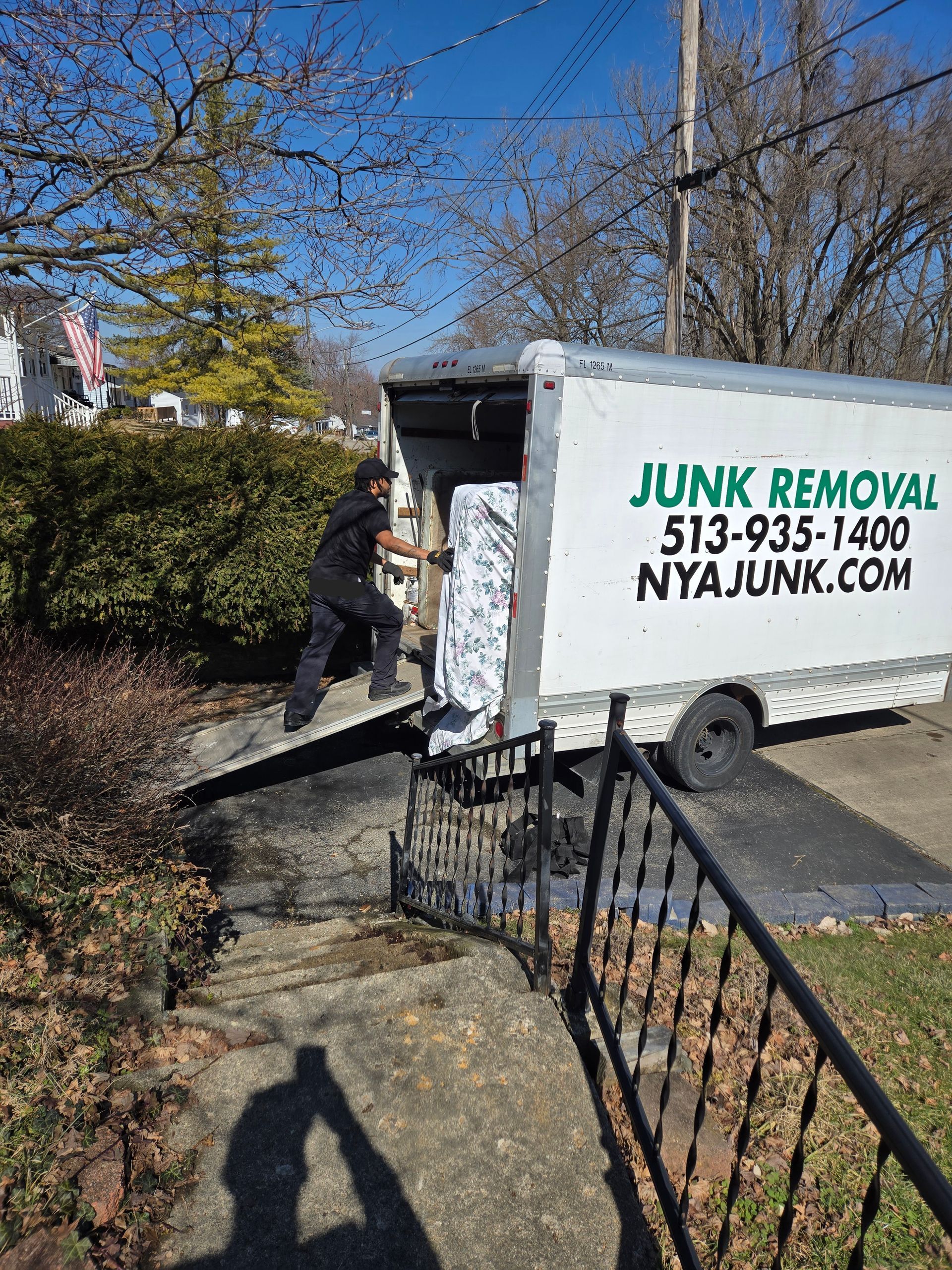 A man is loading a junk removal truck into a driveway.