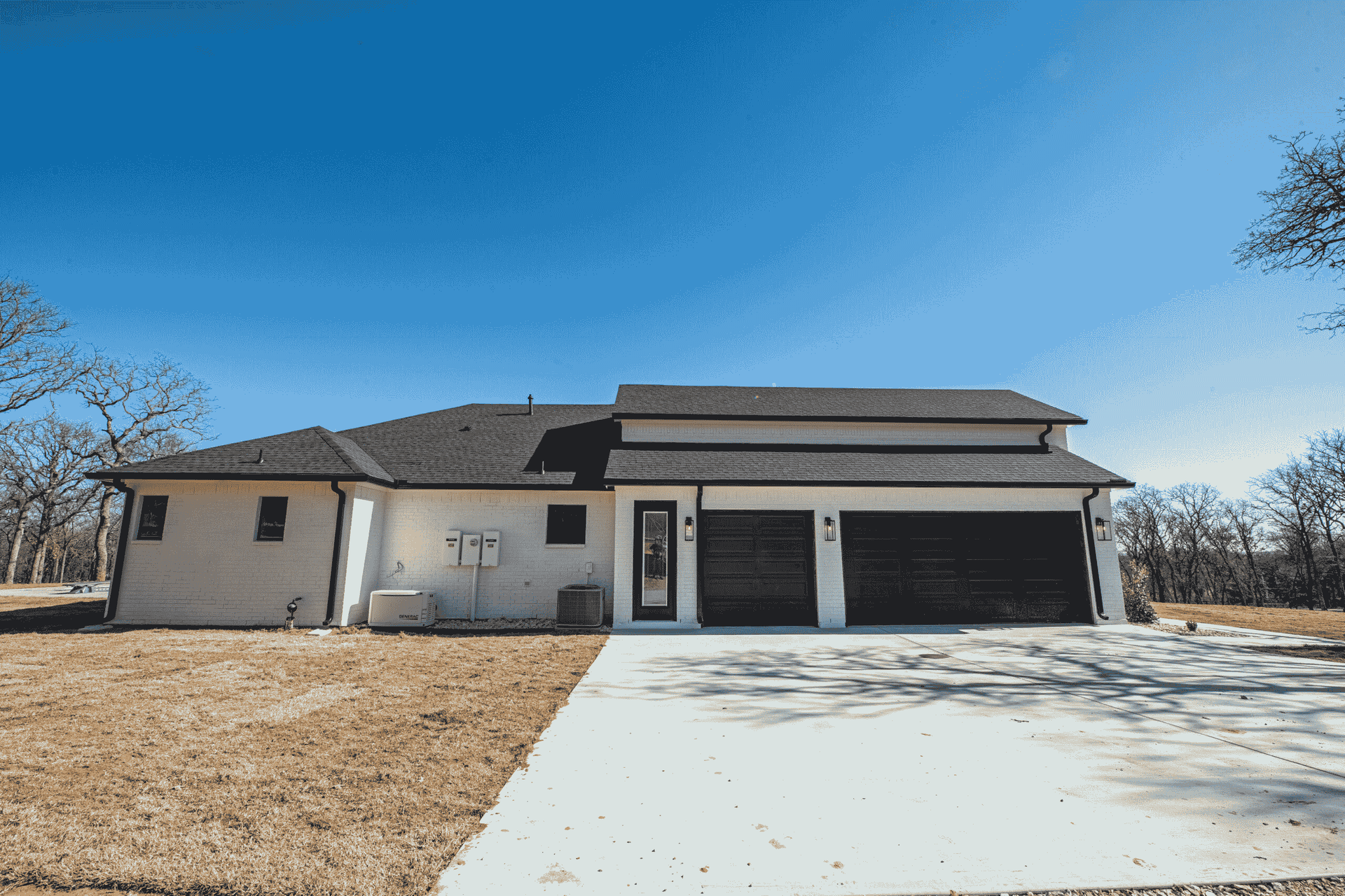 A large white house with a black garage door and a driveway.
