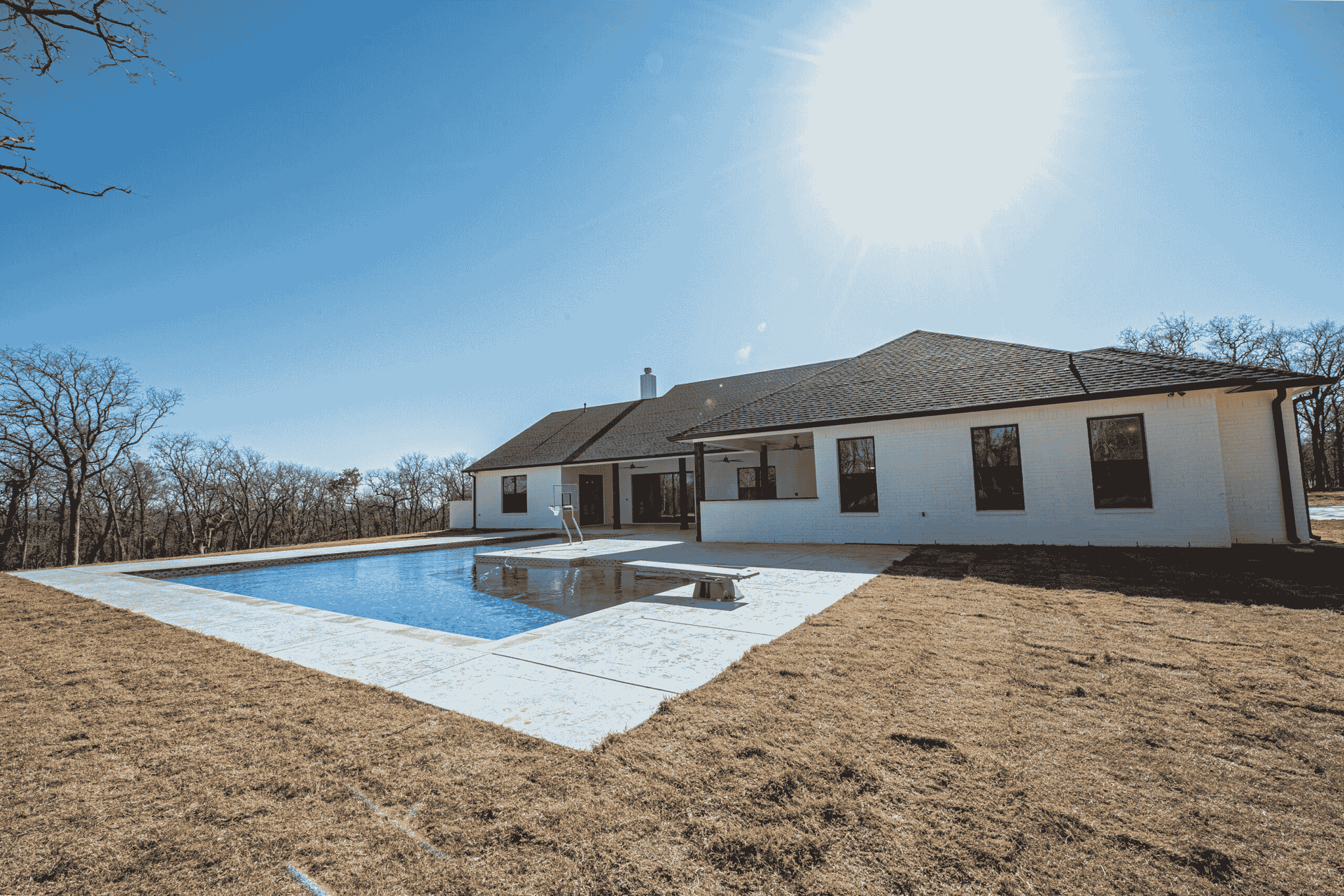 A white house with a large swimming pool in front of it.