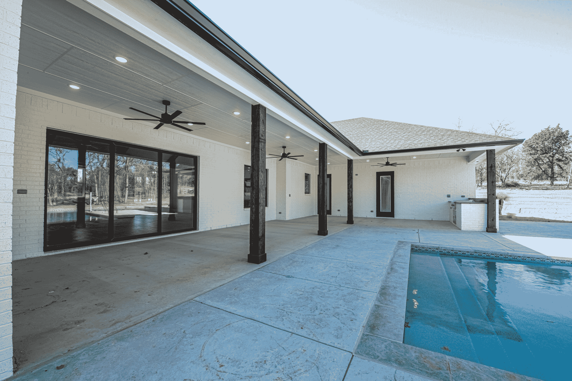 There is a large swimming pool in the backyard of a house.