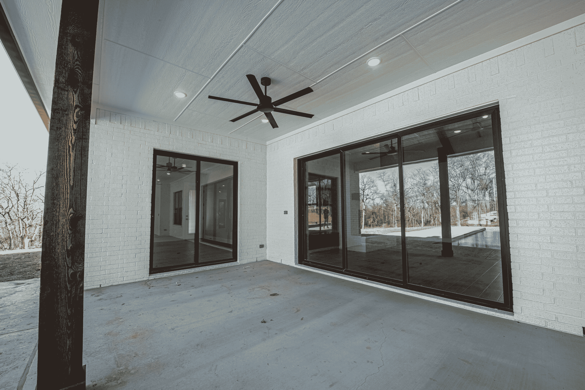 A large patio with sliding glass doors and a ceiling fan.