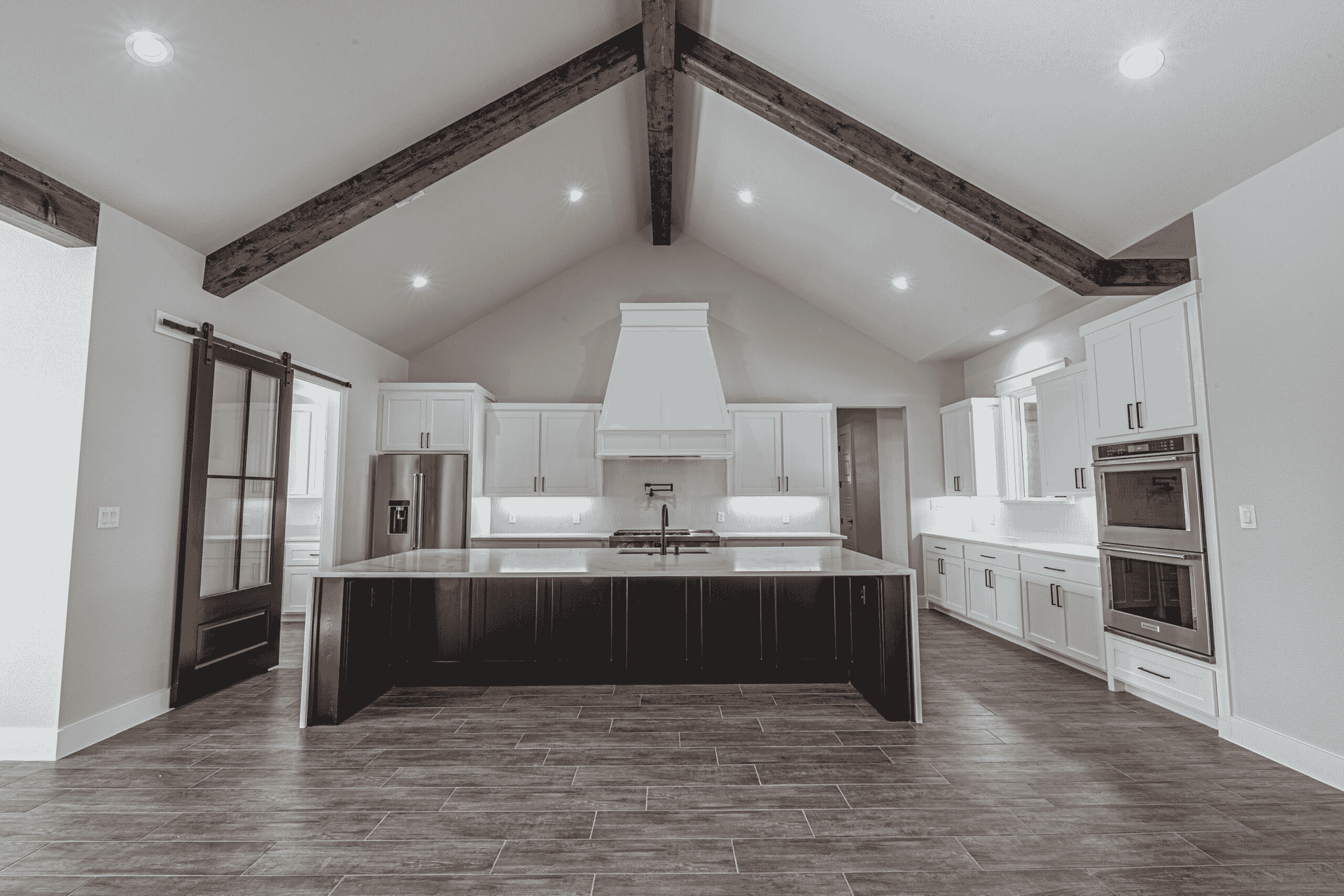 A black and white photo of an empty kitchen with a vaulted ceiling.