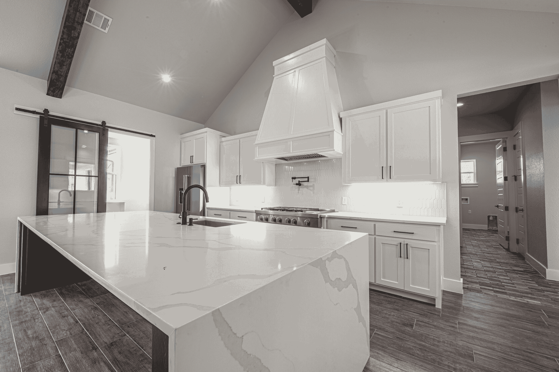 A black and white photo of a kitchen with white cabinets and a large island.