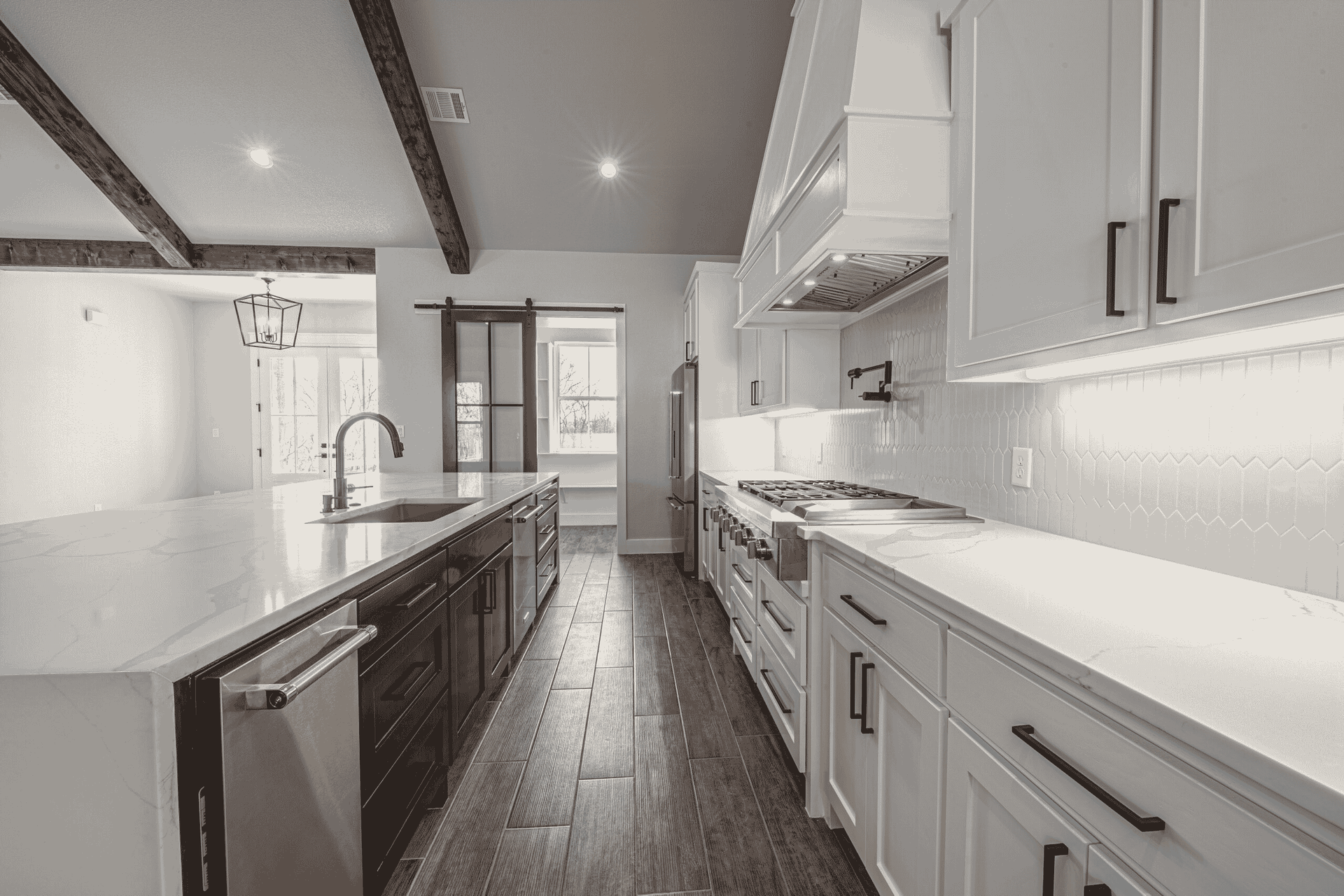 A black and white photo of a kitchen with white cabinets and stainless steel appliances.